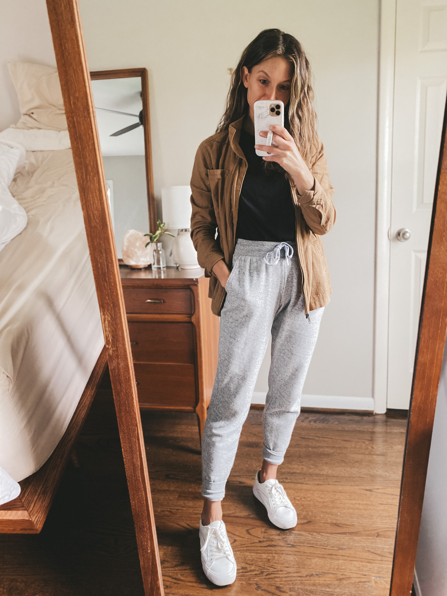 ashley wearing a black tee, tan linen utility jacket, gray joggers and white sneakers
