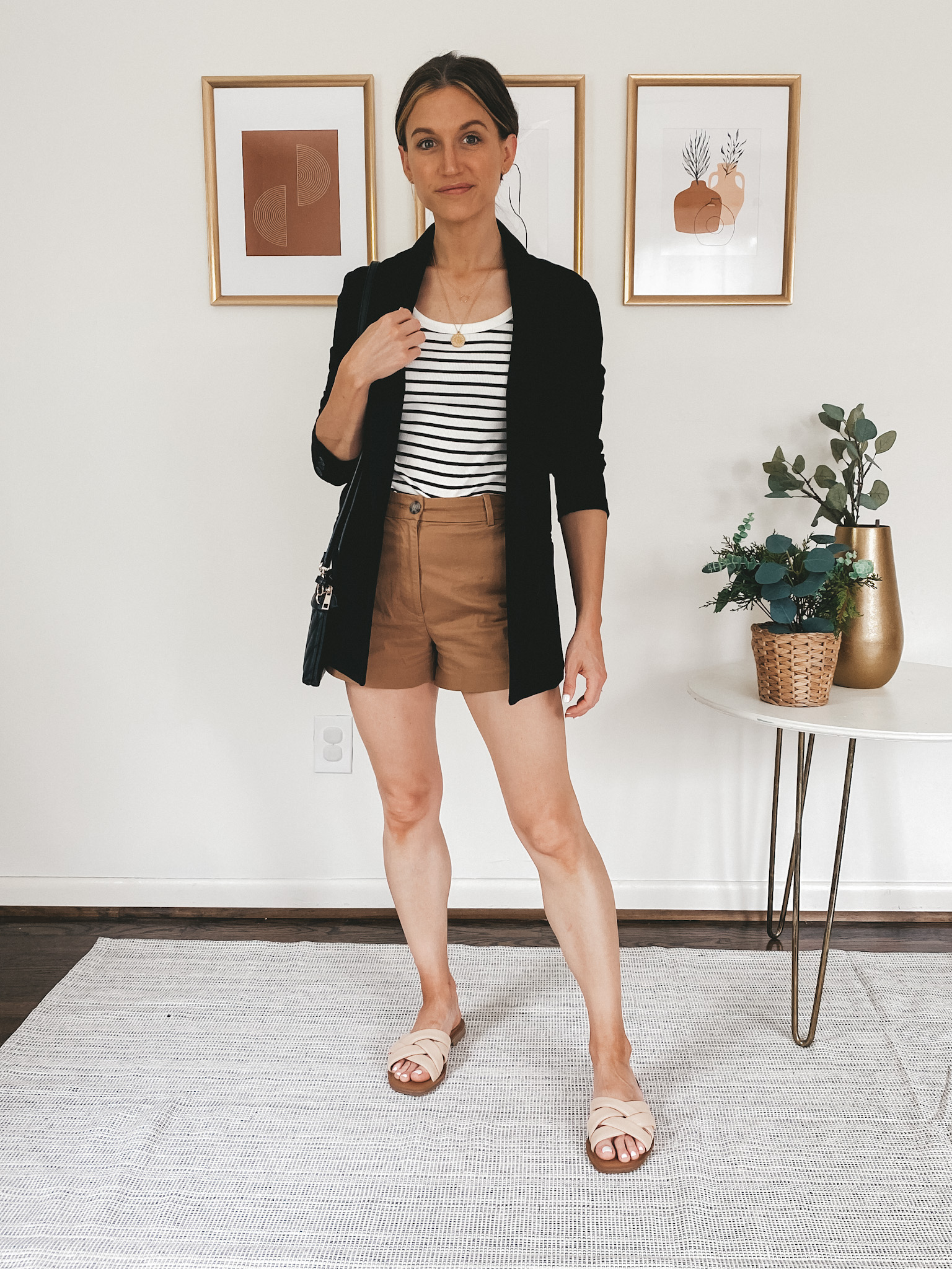 ashley wearing a striped tee, black blazer, brown twill shorts and nude colored padded slides