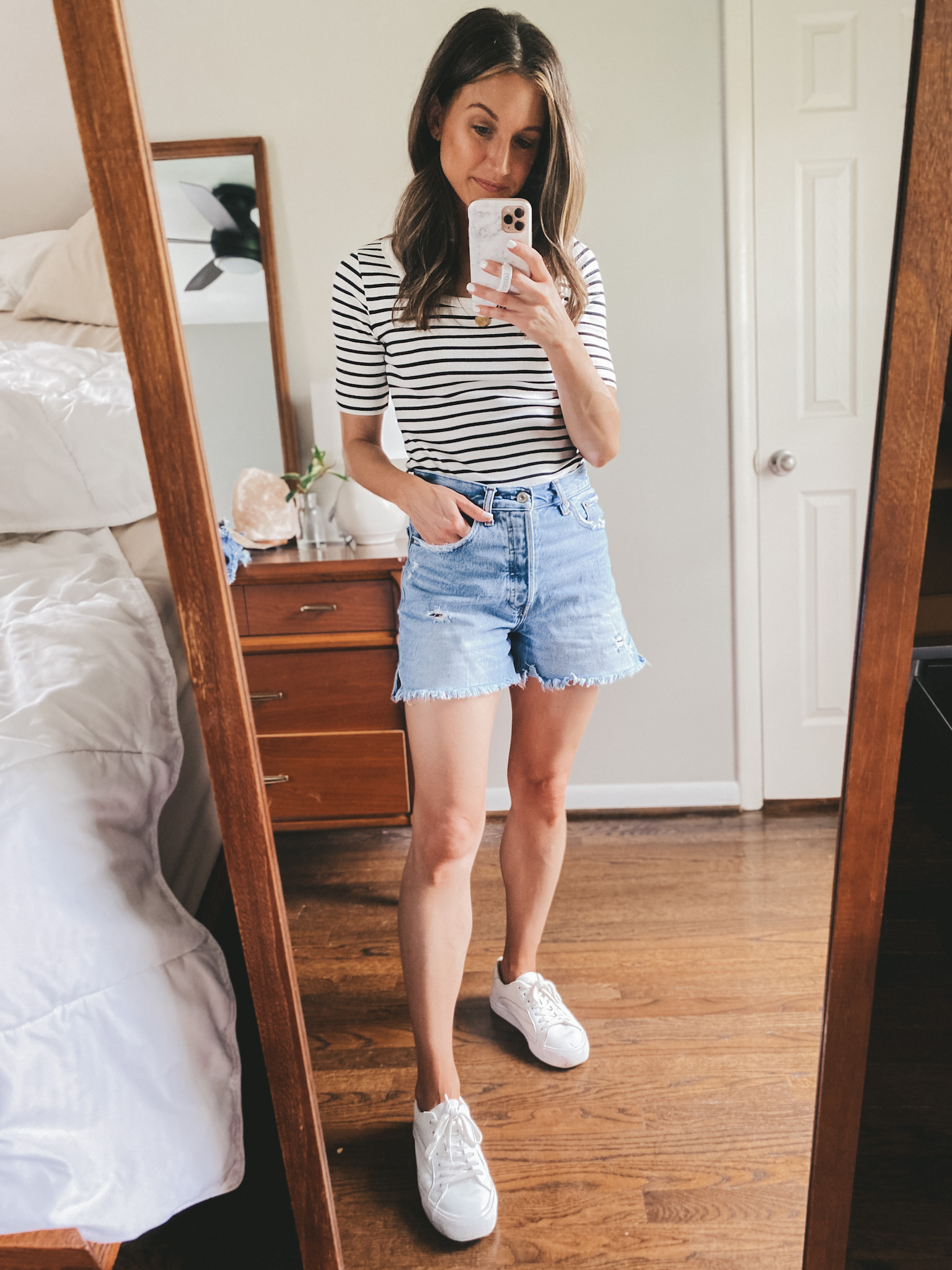a mirror selfie with ashley wearing a fitted striped tee, cut-off denim shorts and white sneakers