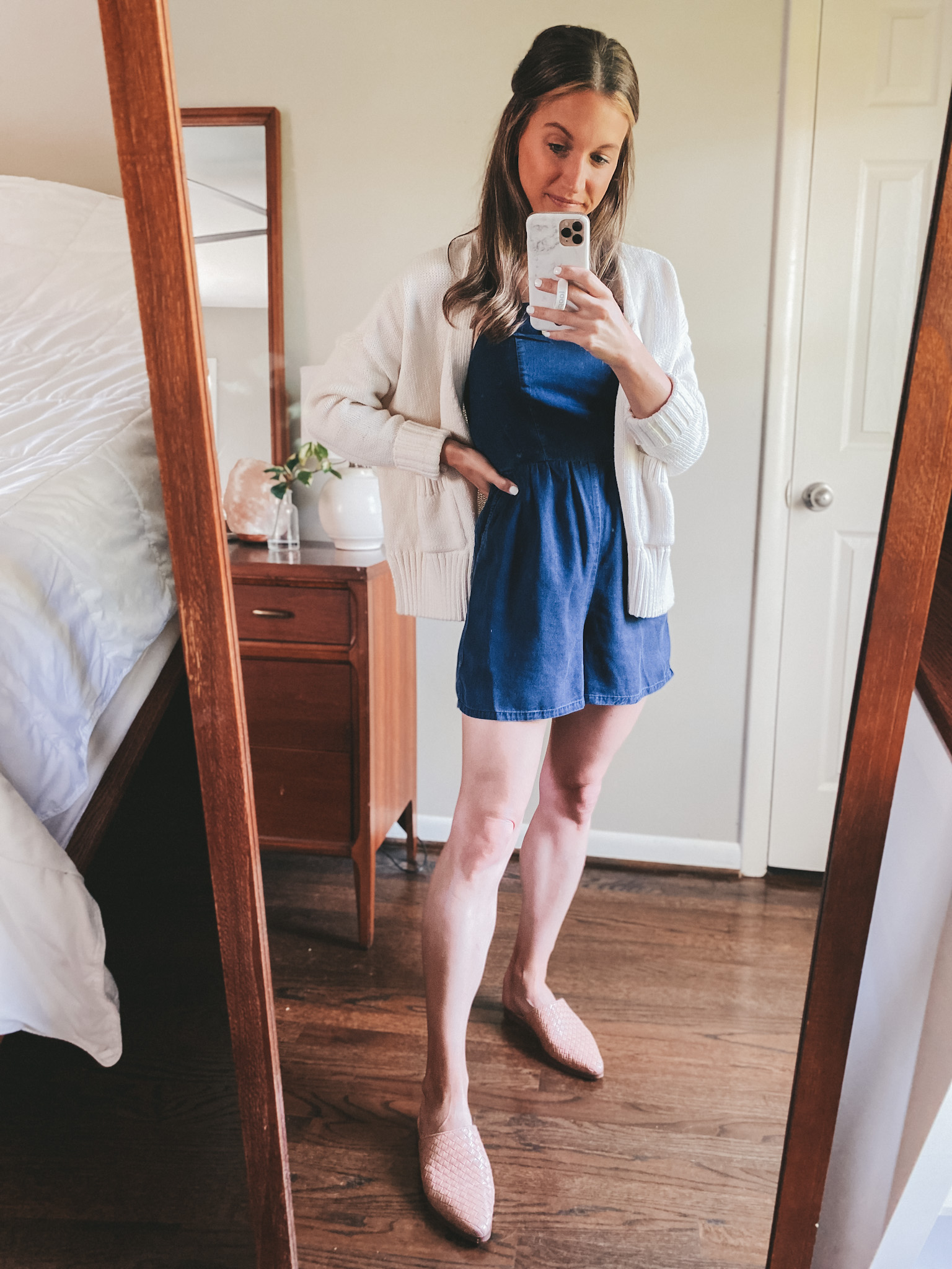 a mirror selfie with ashley wearing a chambray romper and a cream cardigan with tan woven mules