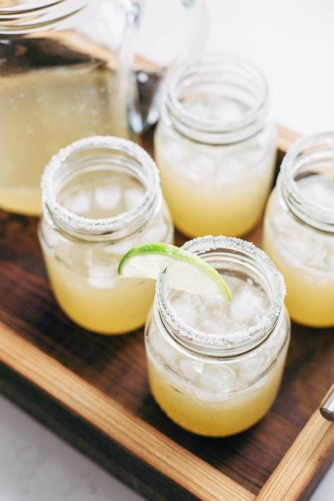 a pitcher and four jars filled with margaritas