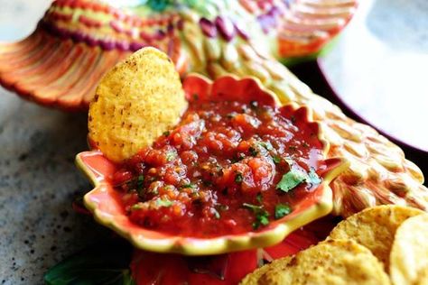 a serving bowl of salsa with chips alongside