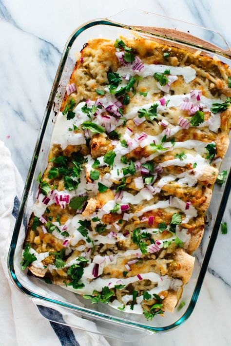 a clear casserole dish with enchiladas drizzled with a sour cream sauce