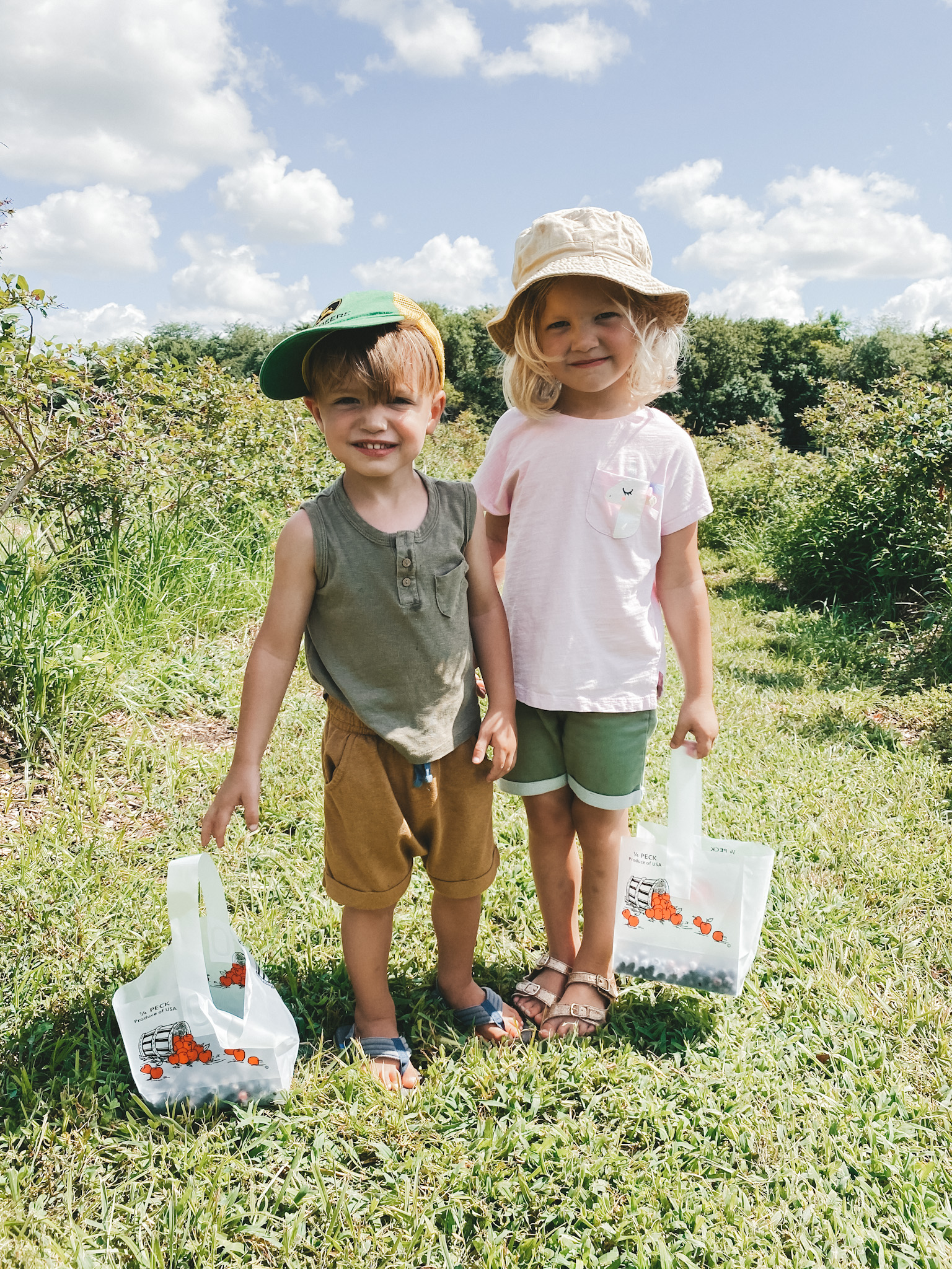 two young kids standing next to each other holding 2 bags with blueberries at Gieringer