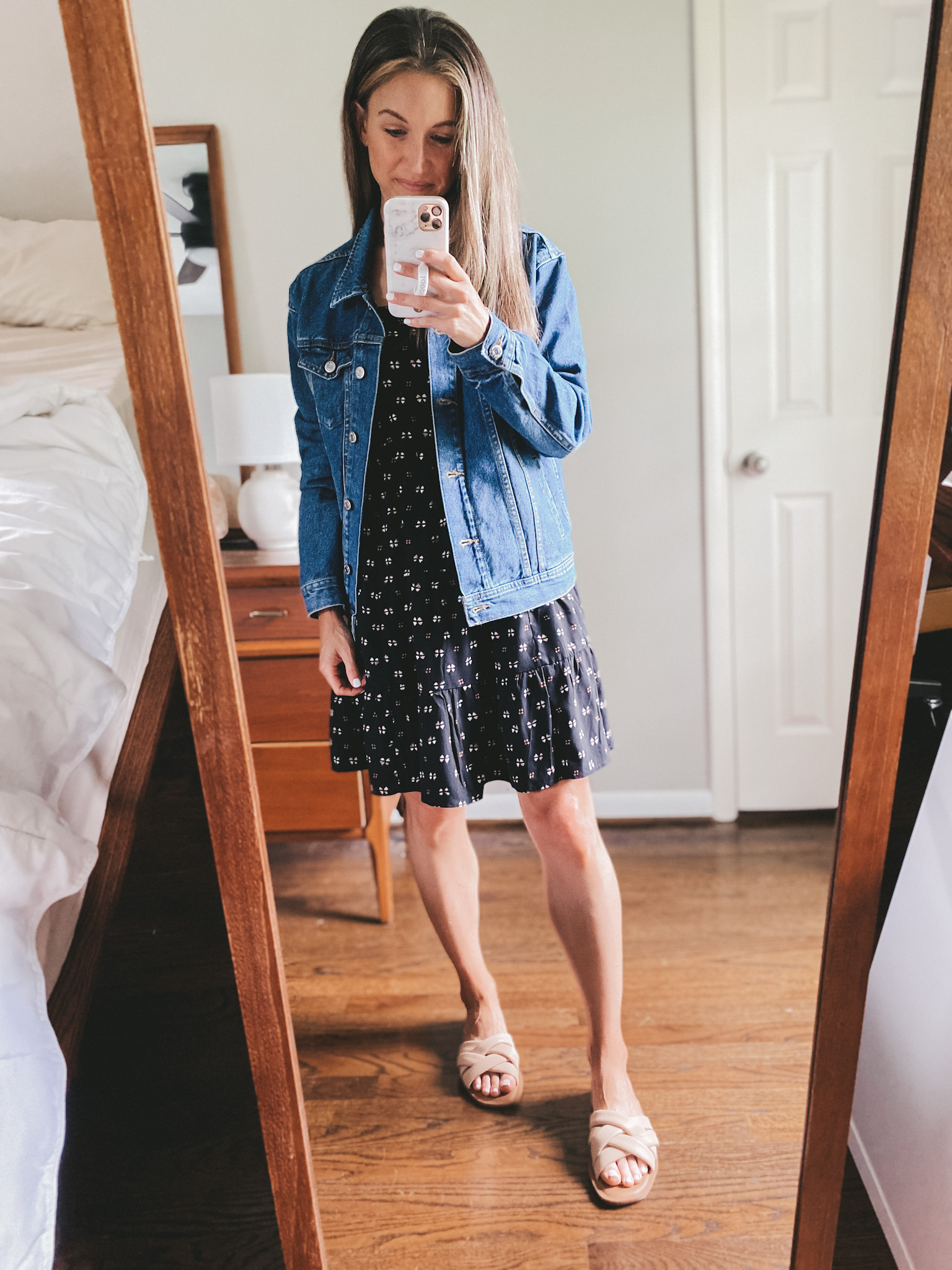 ashley wearing a black tiered knee length dress, denim jacket and nude padded slides