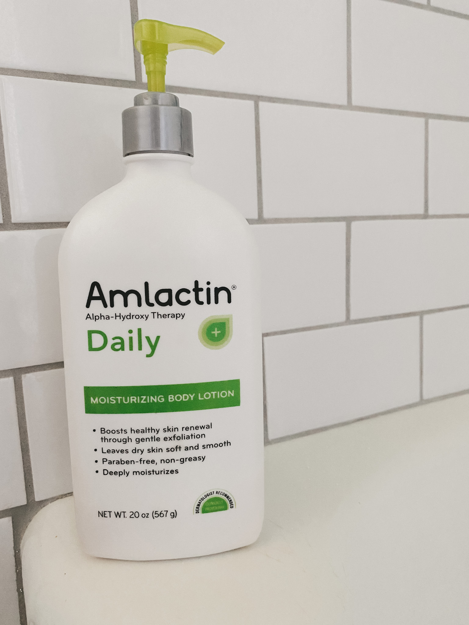 a bottle of AmLactin Daily Moisturizing Lotion; a subway tile bathroom wall