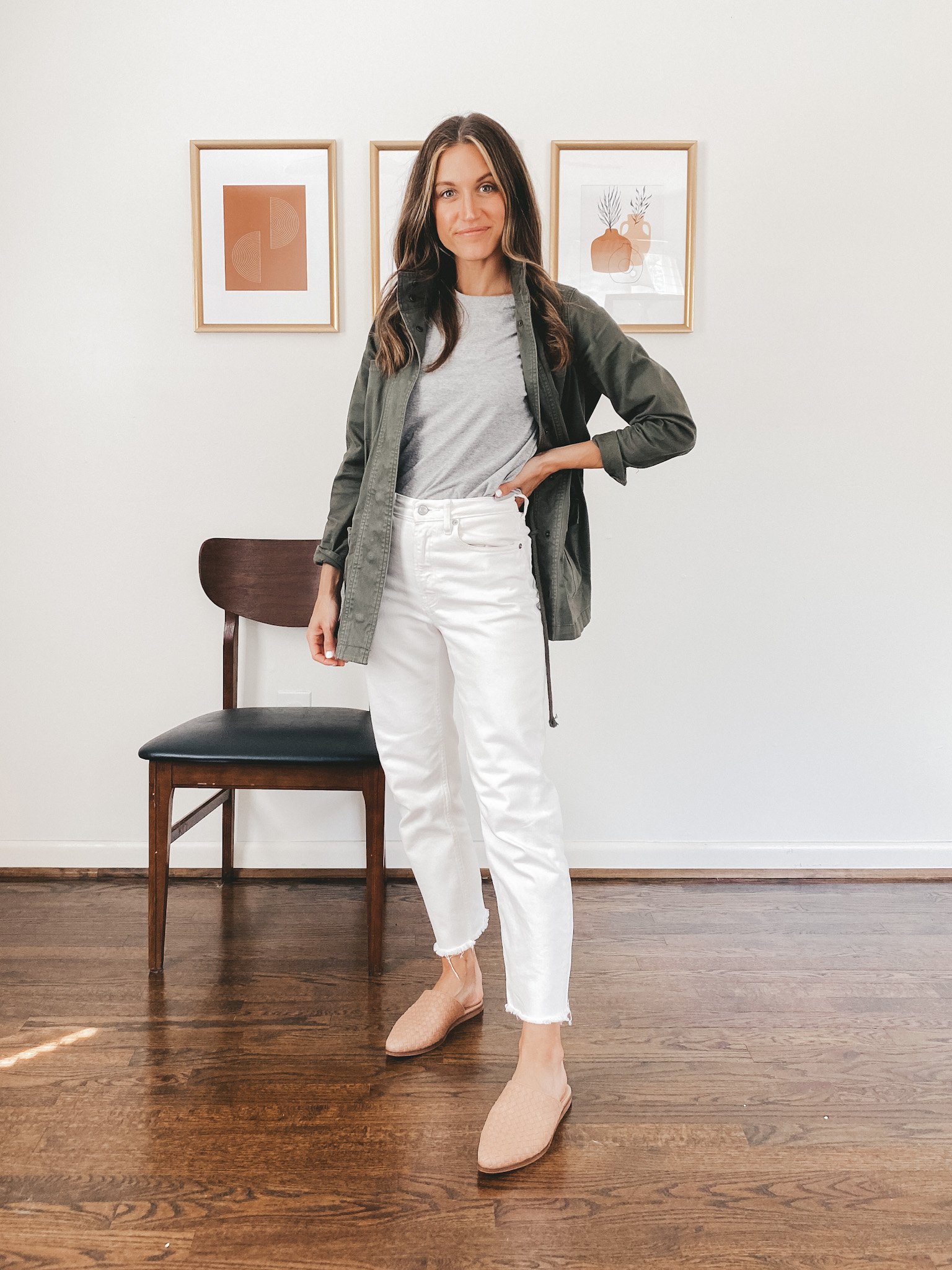 ashley wearing a gray tee, green utility jacket, white straight leg denim, and tan woven mules