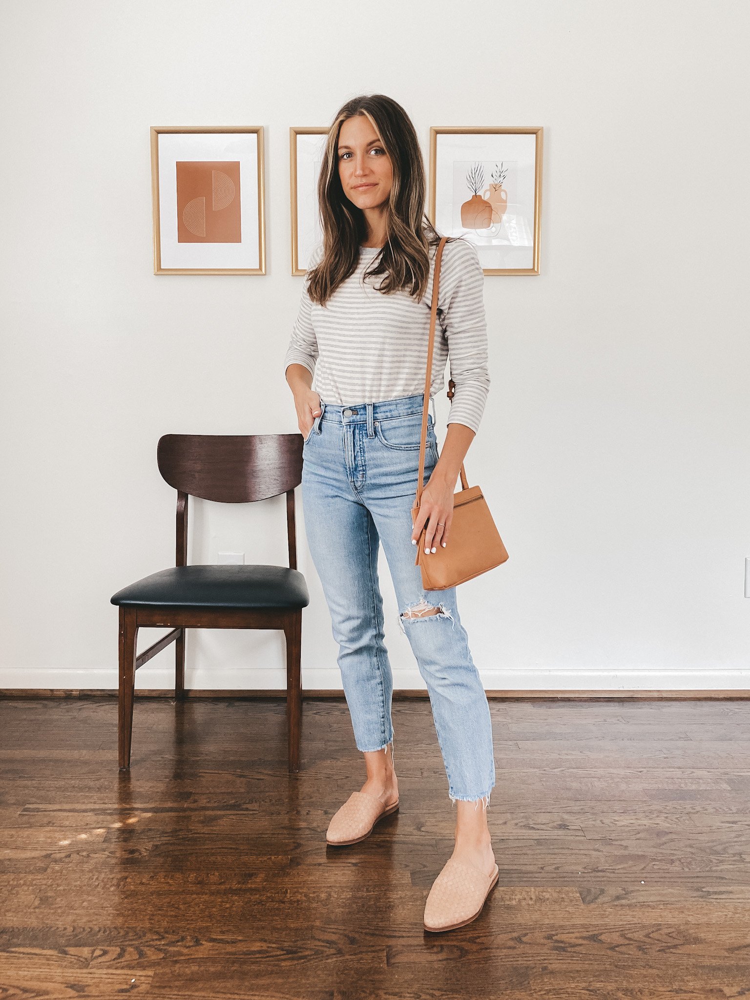 ashley wearing a striped tee, light wash straight leg jeans, tan woven mules and a camel colored crossbody bag