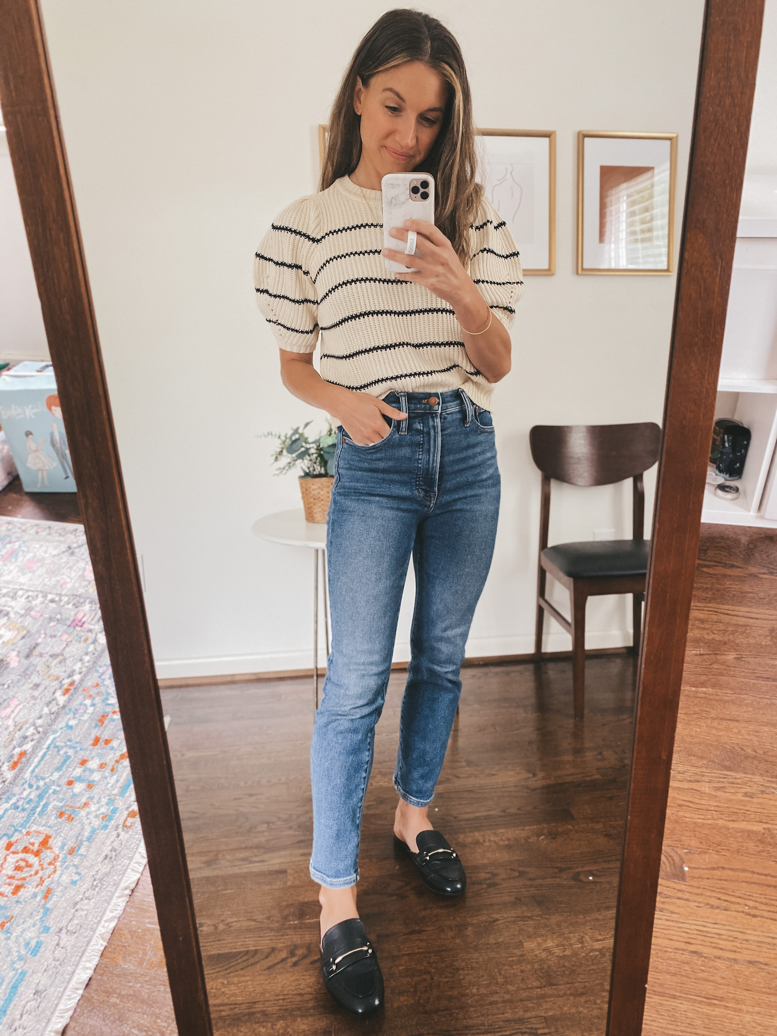 ashley wearing a puff sleeve black and cream striped sweater, mid-wash straight leg denim, and black mules