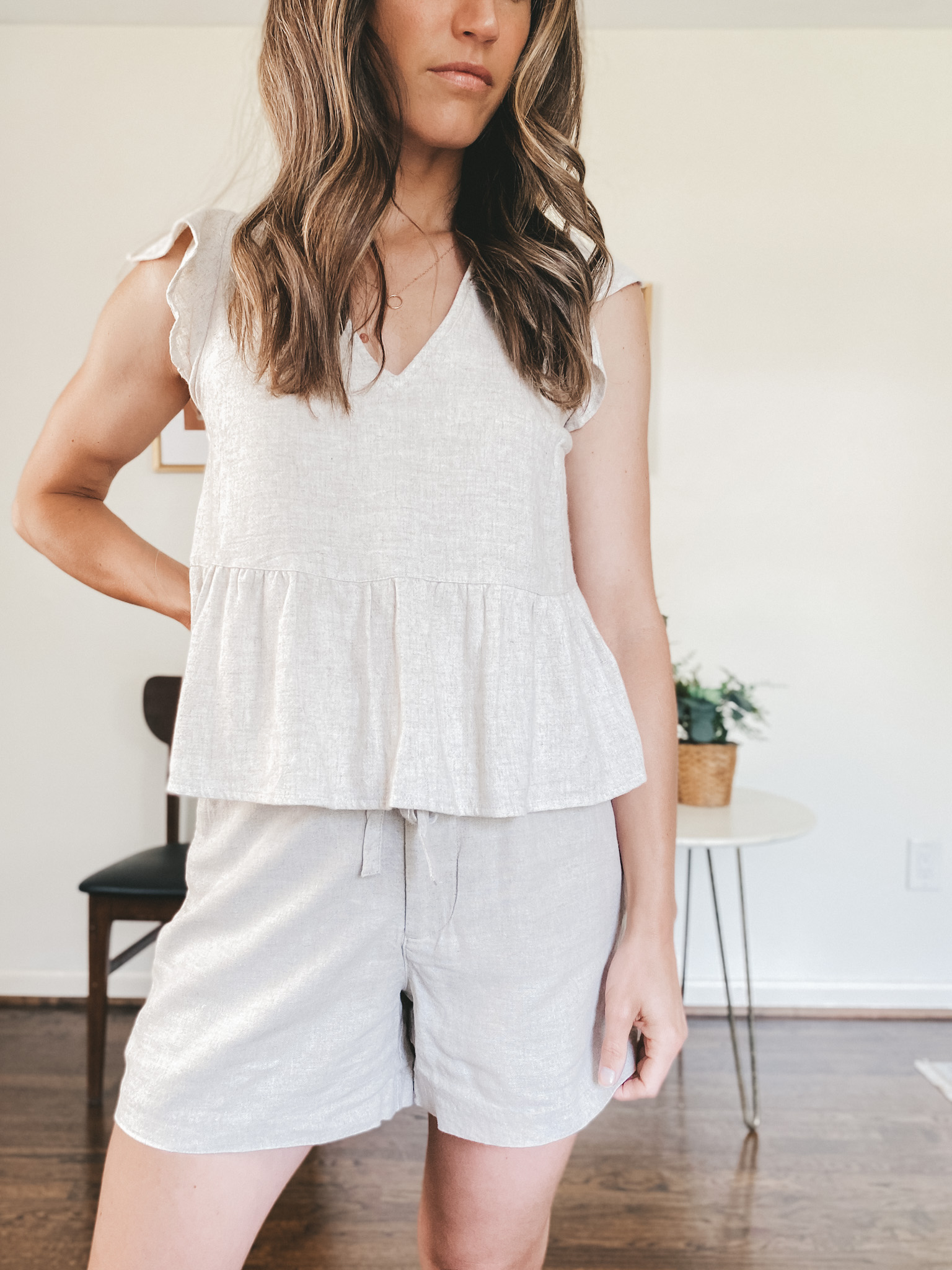 ashley wearing a tan linen blend matching set with a flutter sleeve peplum top and tie waste shorts