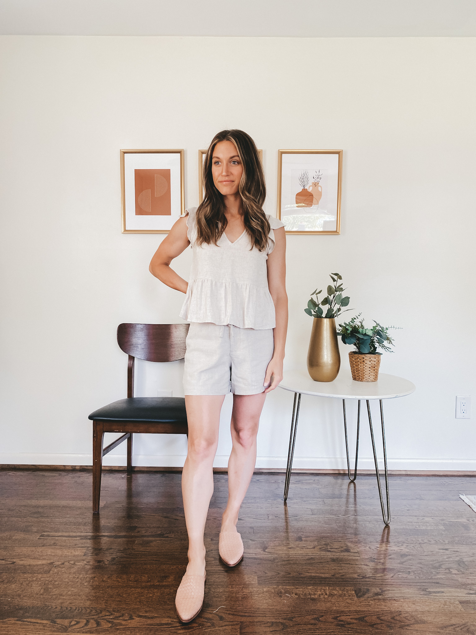 ashley wearing a tan linen blend matching set with a flutter sleeve v-neck top and tie waist shorts with tan woven mules