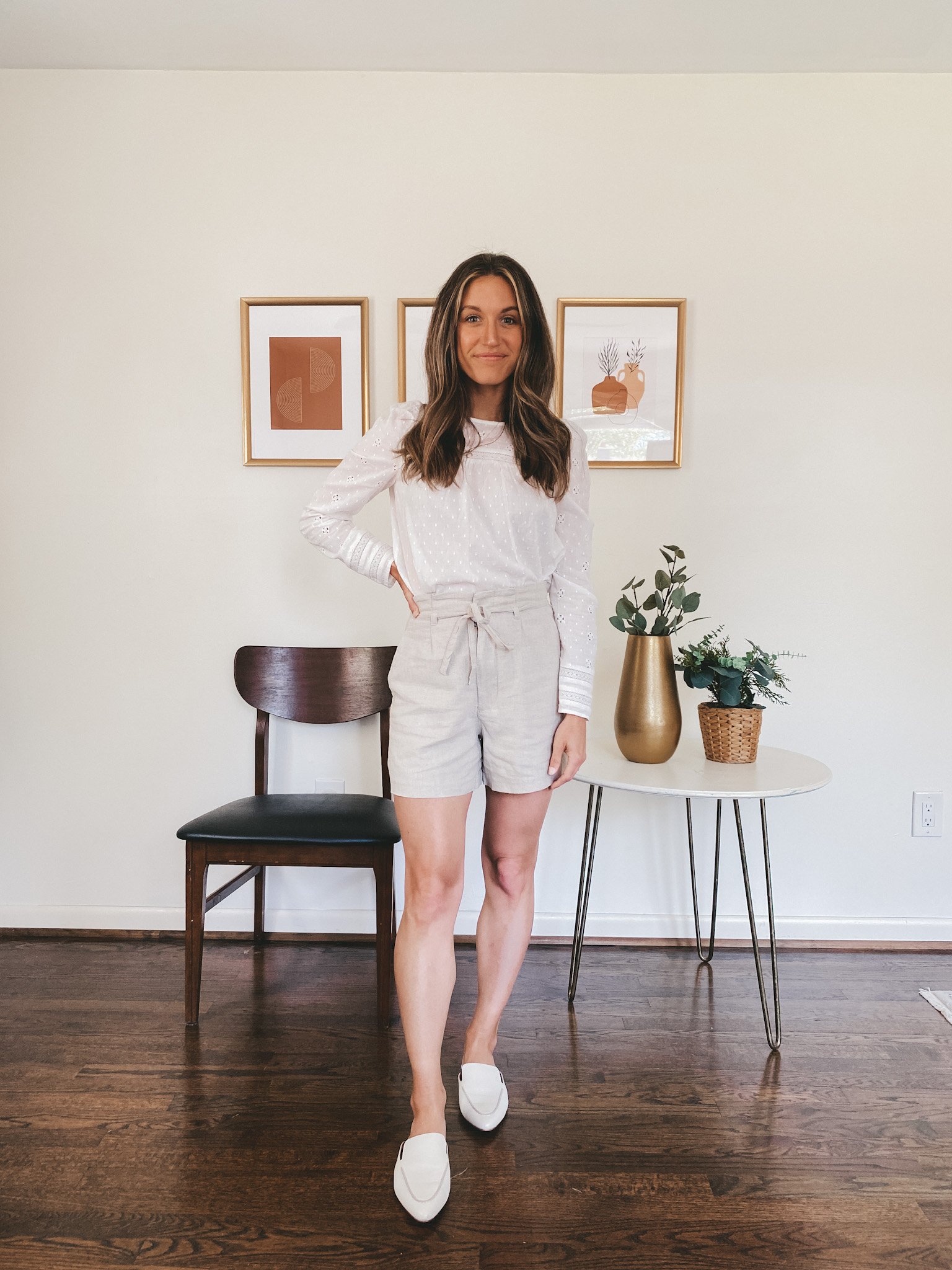 ashley wearing a long sleeved white eyelet top, tan linen blend shorts and white mules