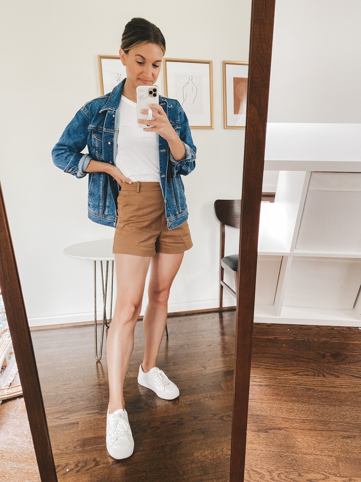 ashley wearing a white tank, denim jacket, brown cotton shorts and white sneakers