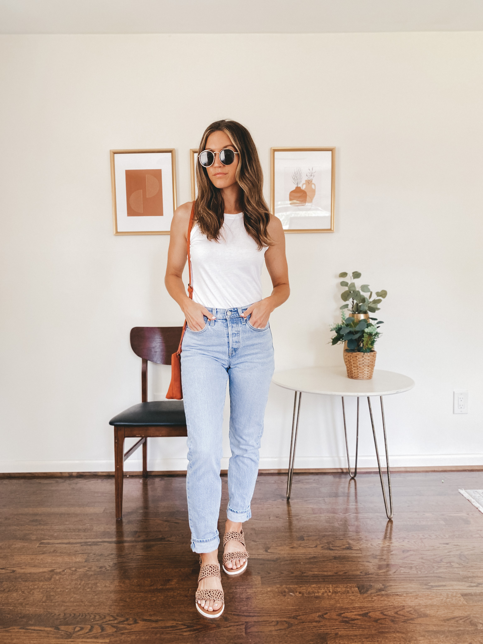 ashley wearing a white tank, light wash mom jeans, and leopard print mules with round gold frame sunglasses and a red crossbody bag