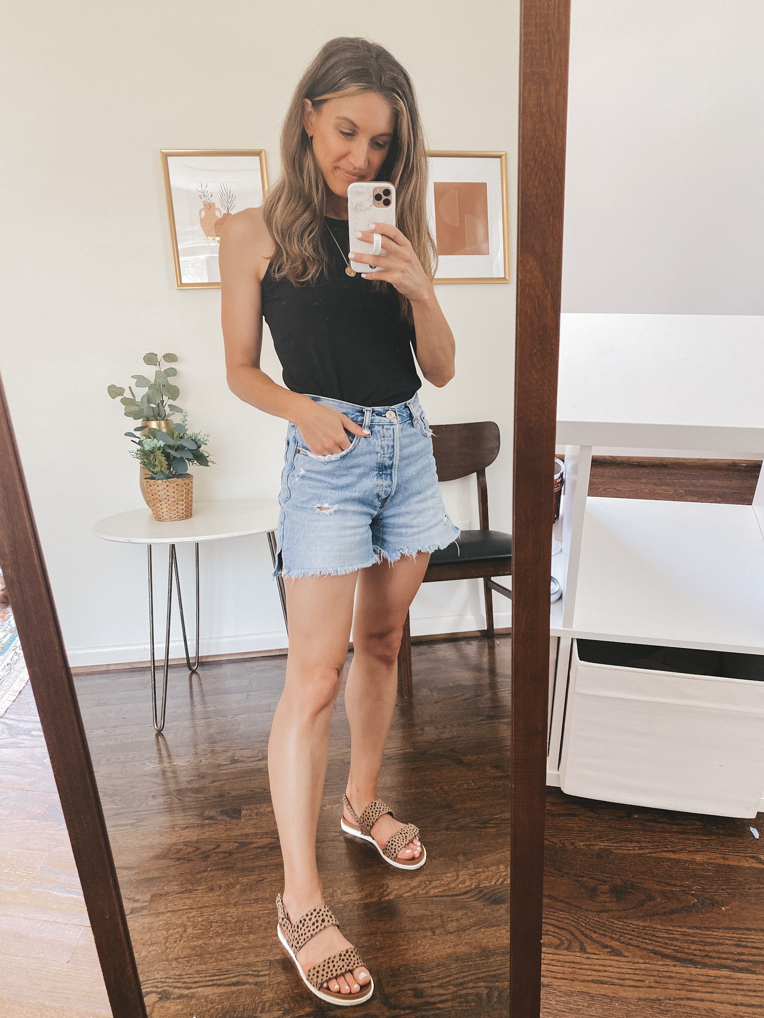 ashley wearing a black tank, cut-off denim shorts and leopard print sandals