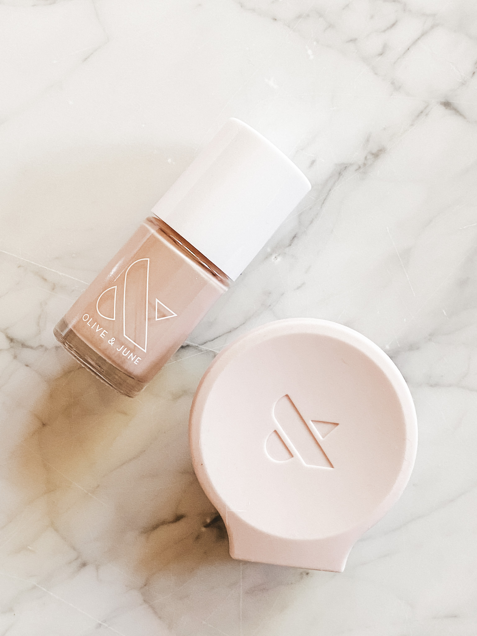 a nail polish bottle and a pink poppy on a marble table