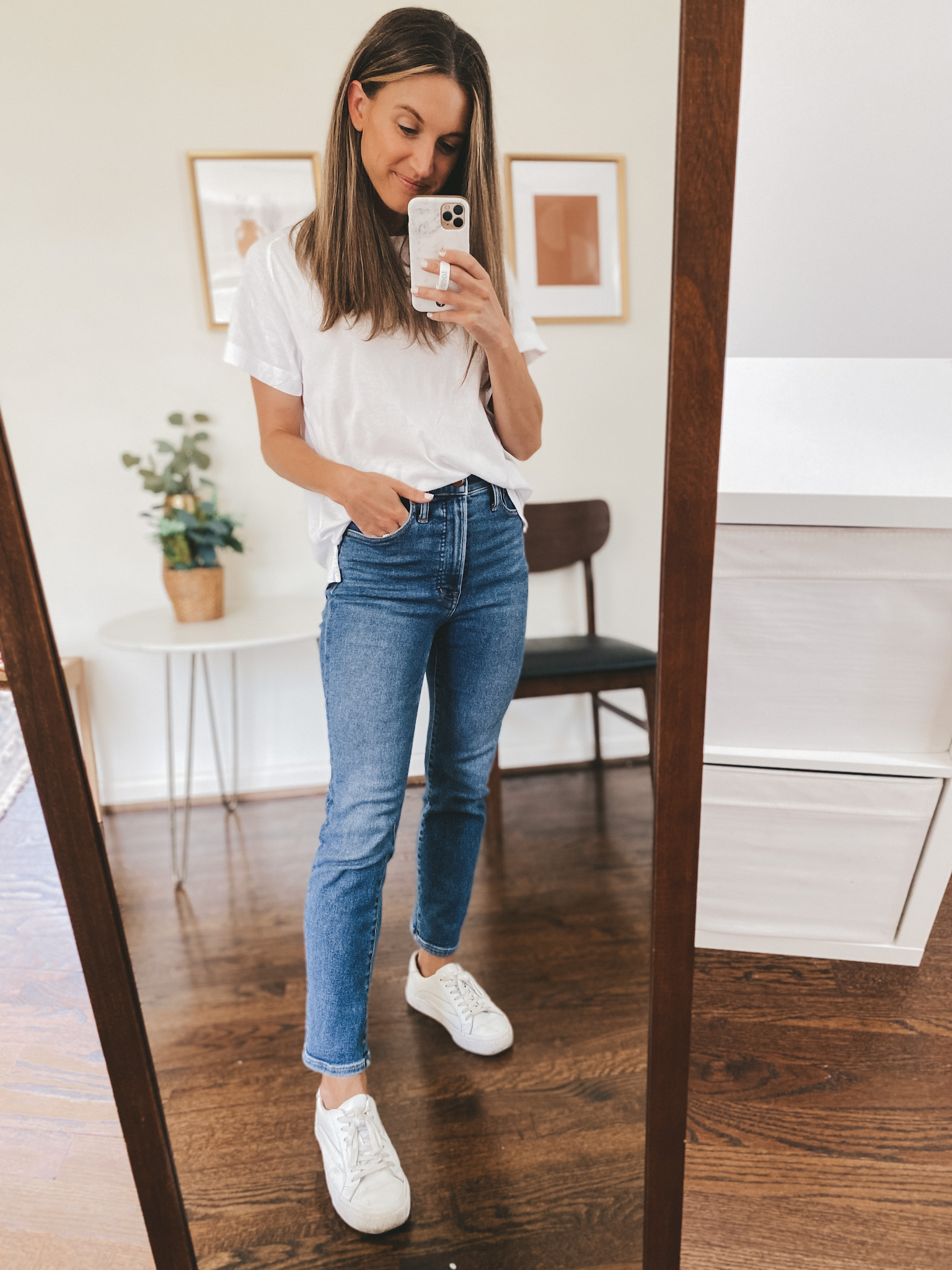 ashley wearing an oversized white tee, mid-wash denim and white sneakers