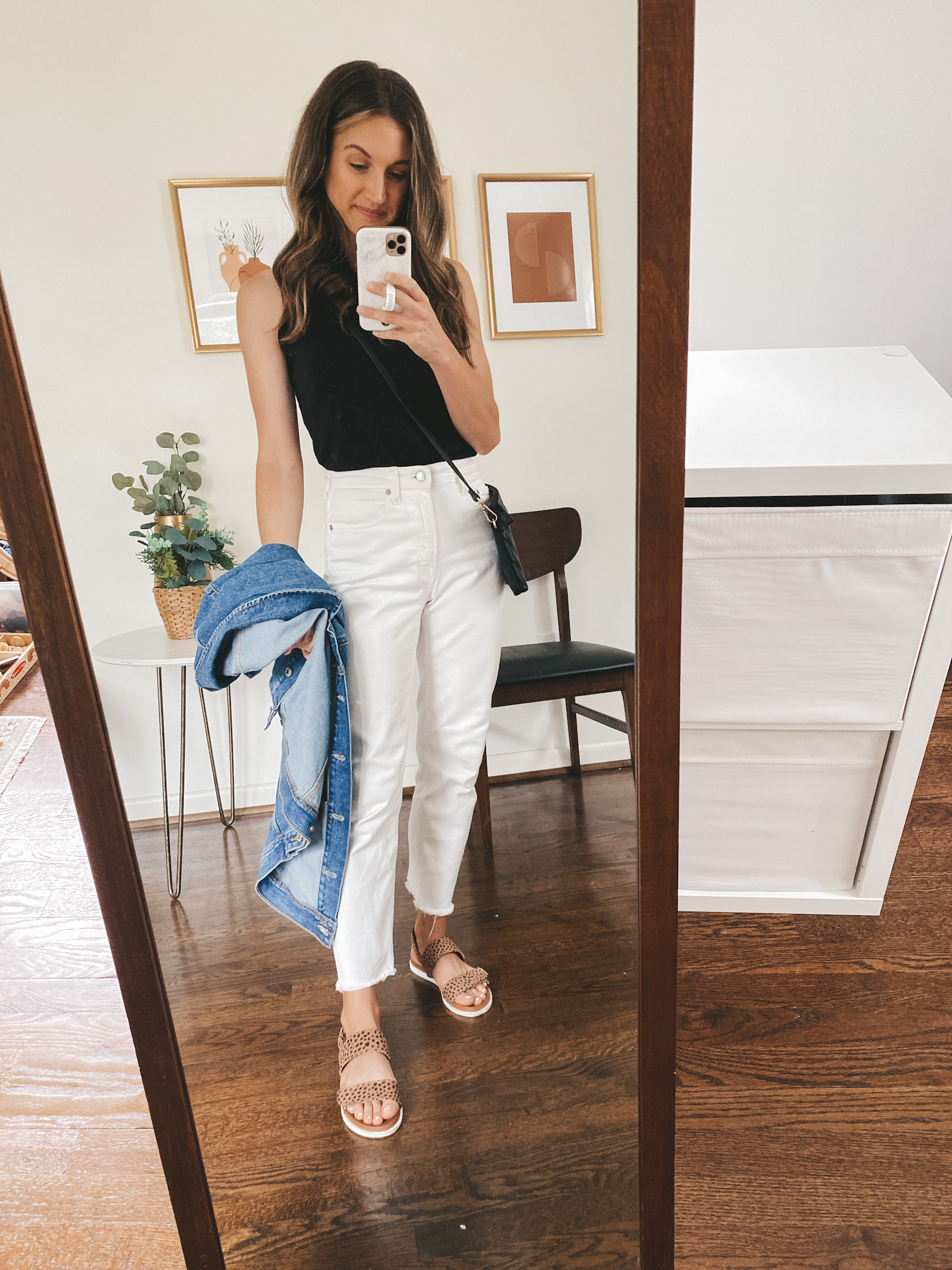 ashley wearing a black tank, white jeans, leopard print sandals and carrying a denim jacket