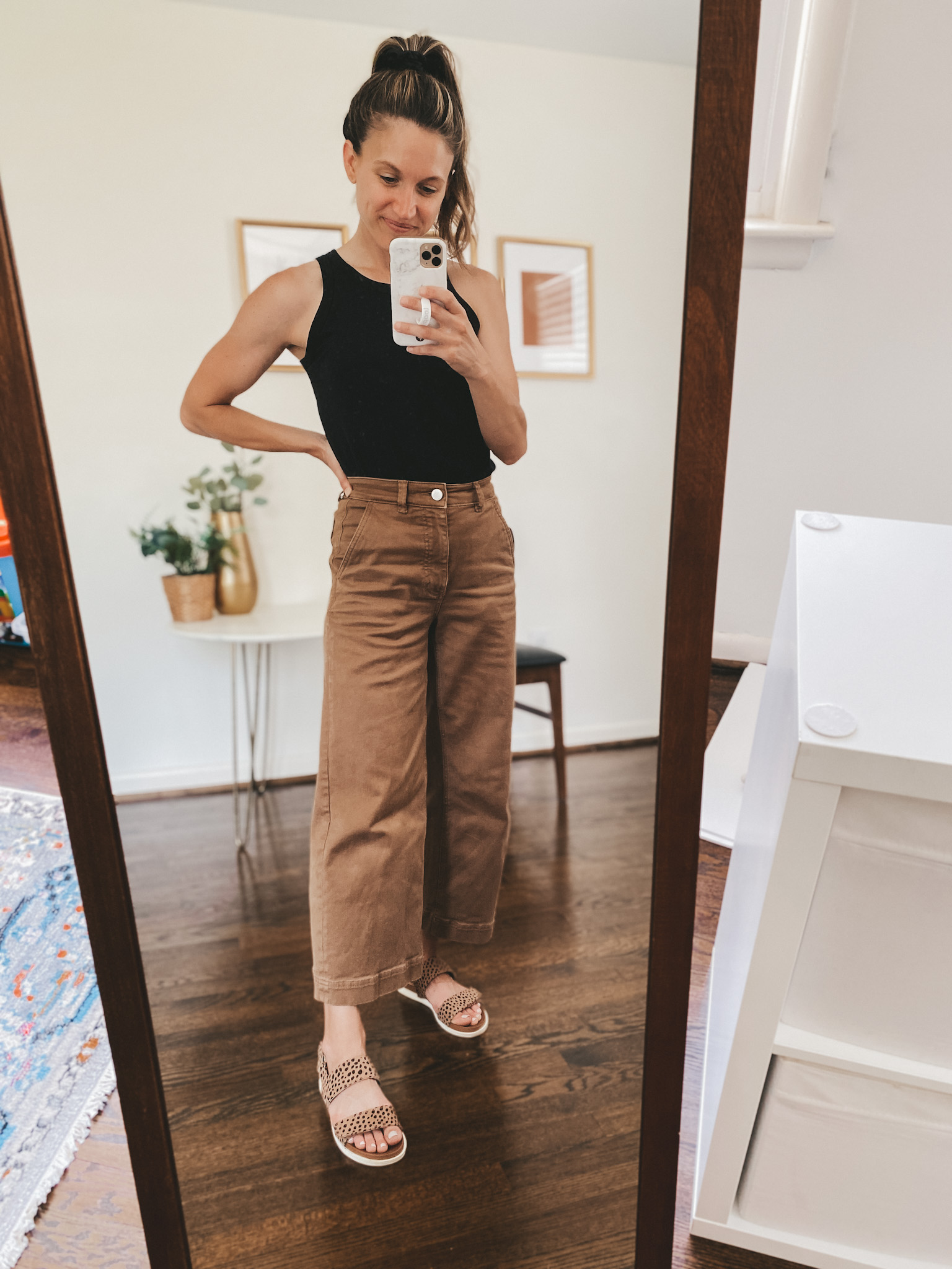 ashley wearing a black tank, brown wide leg cropped pants, and leopard print sandals