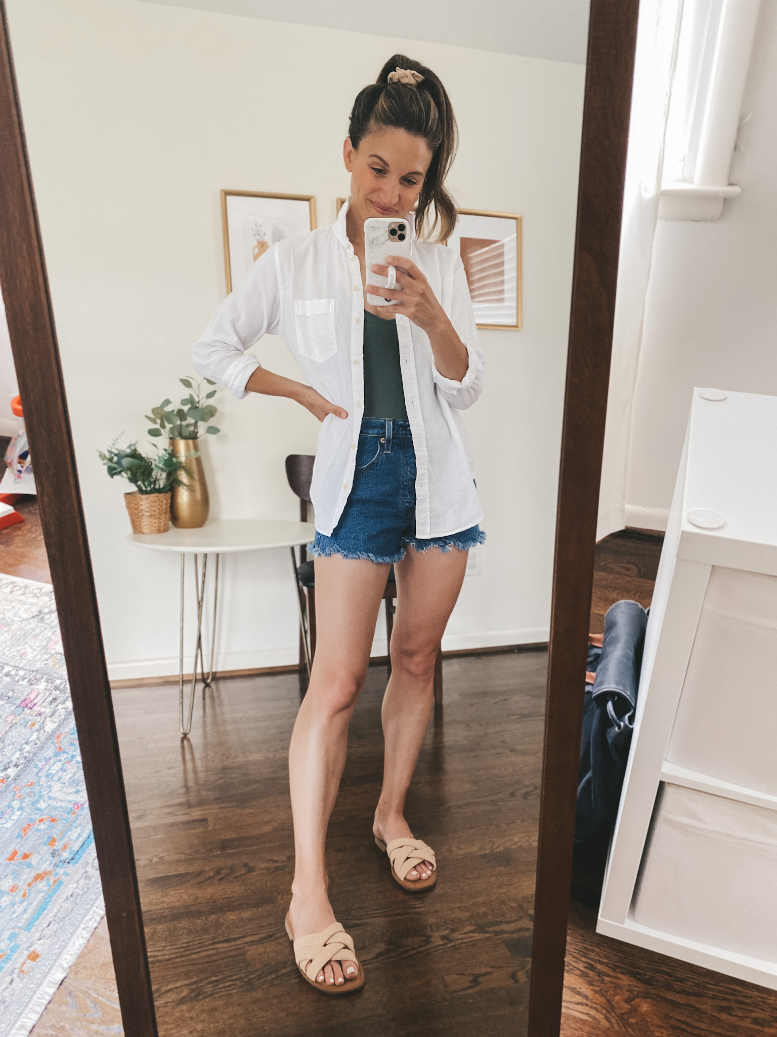 ashley wearing an olive green one piece swimsuit, white button down, cut-off denim shorts and nude padded slides