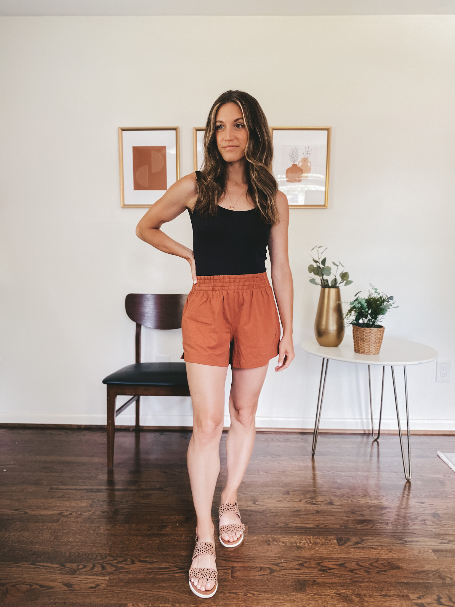 ashley wearing a black sleeveless bodysuit and rust colored jersey shorts