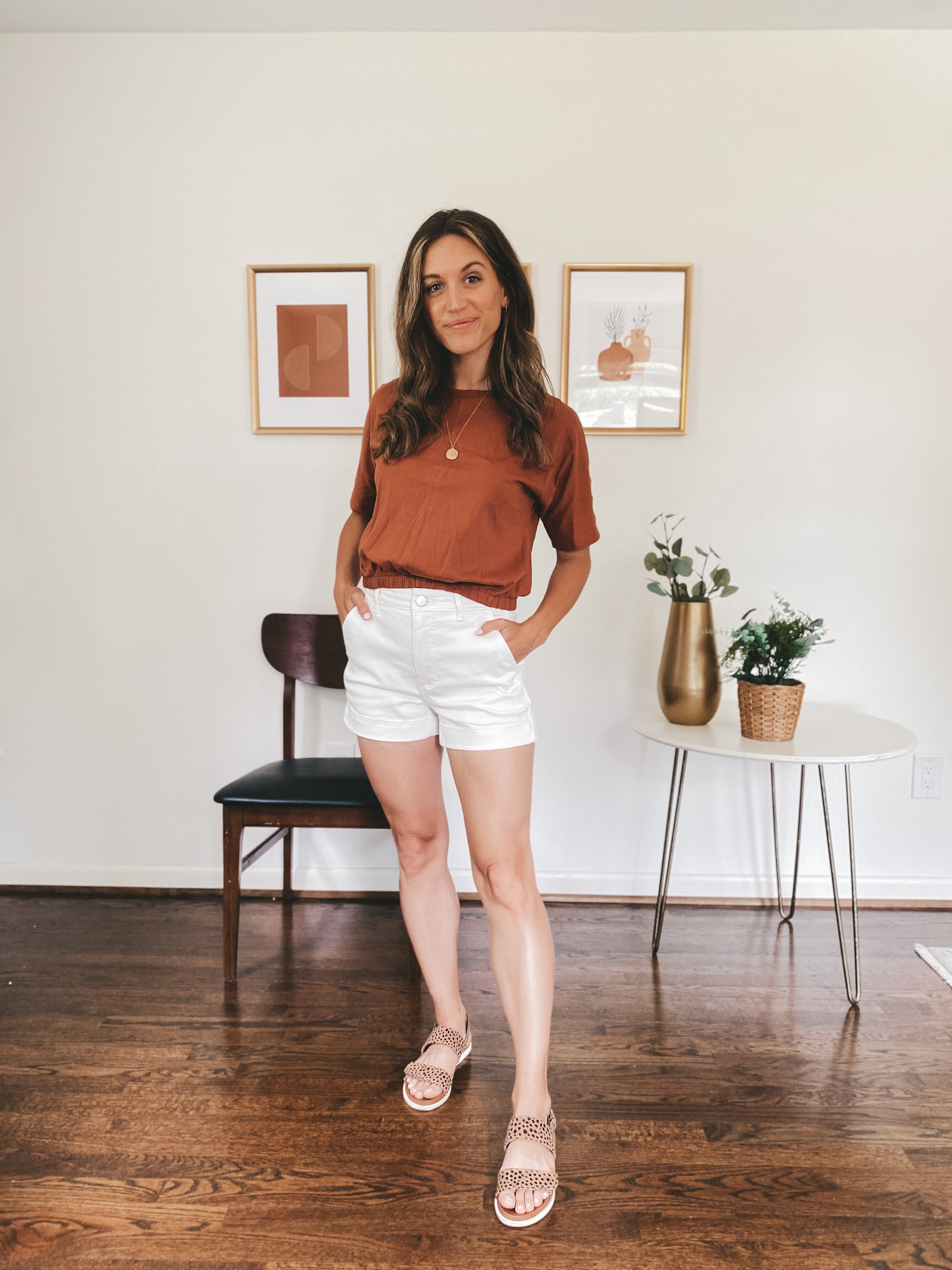 ashley wearing a rust colored tee, white twill shorts and leopard print sandals