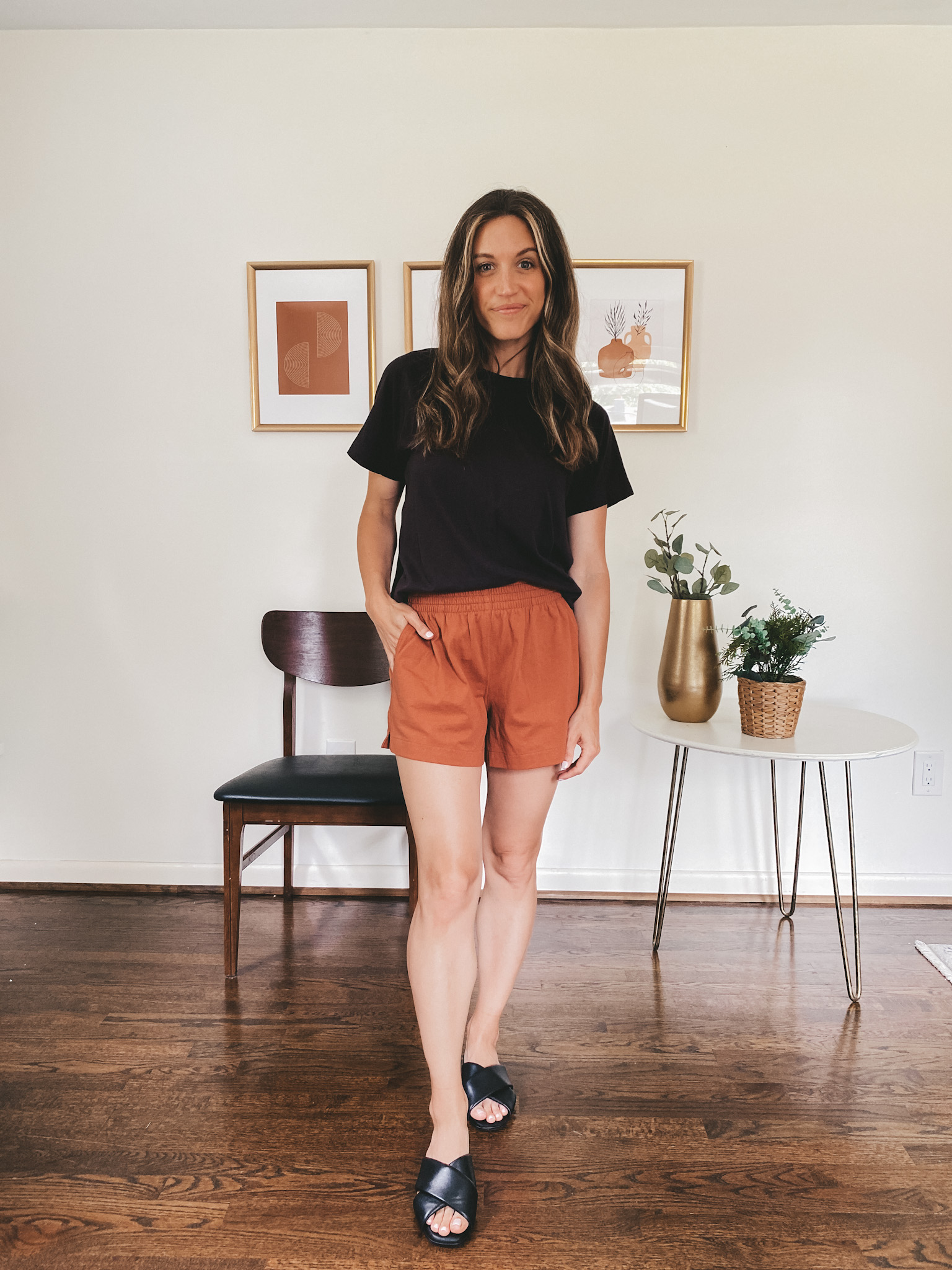 ashley wearing a black tee, rust colored jersey shorts and black crossover slides