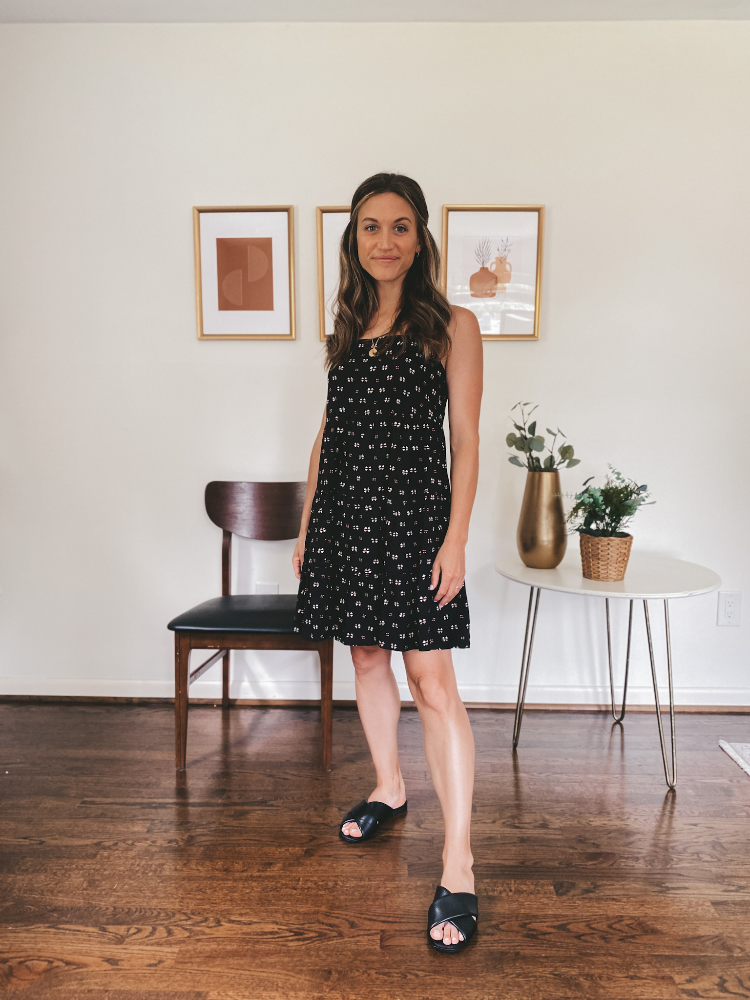 ashley wearing a knee length black patterned dress and black crossover slides