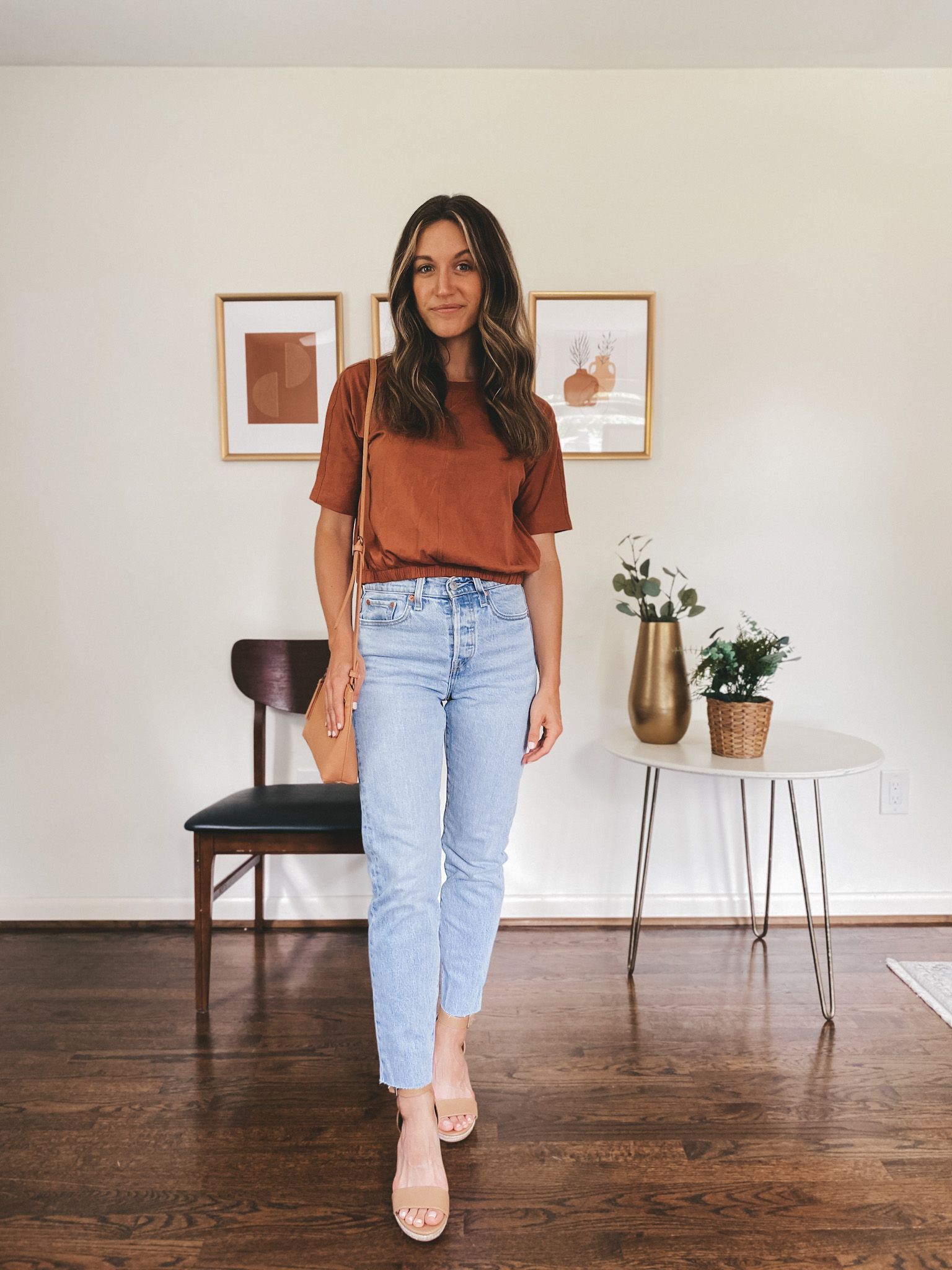 ashley wearing a rust colored bubble tee, light wash straight leg denim and tan colored espadrilles with a camel colored crossbody bag