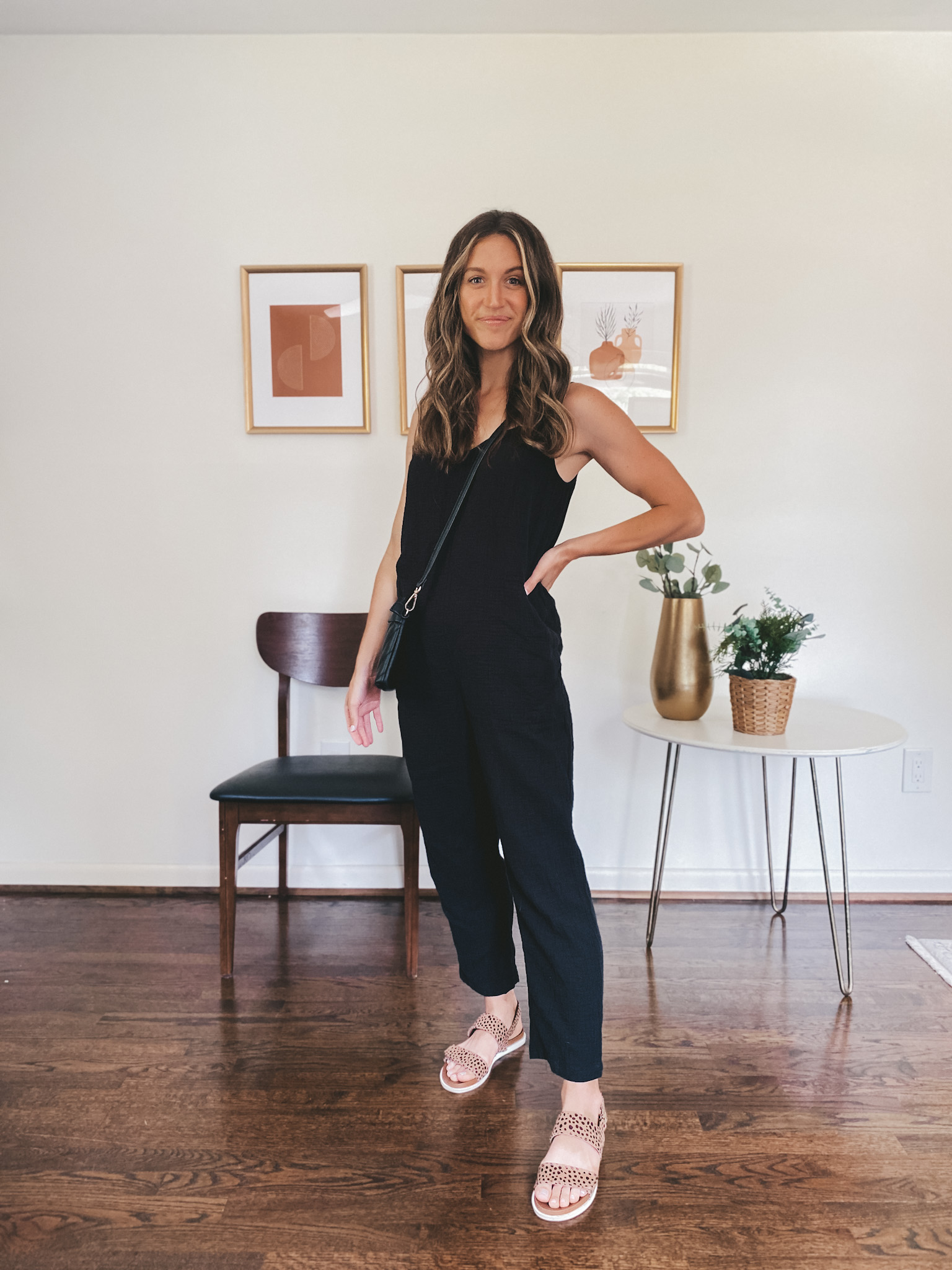 ashley wearing a black jumpsuit, leopard print sandals and a black quilted bag