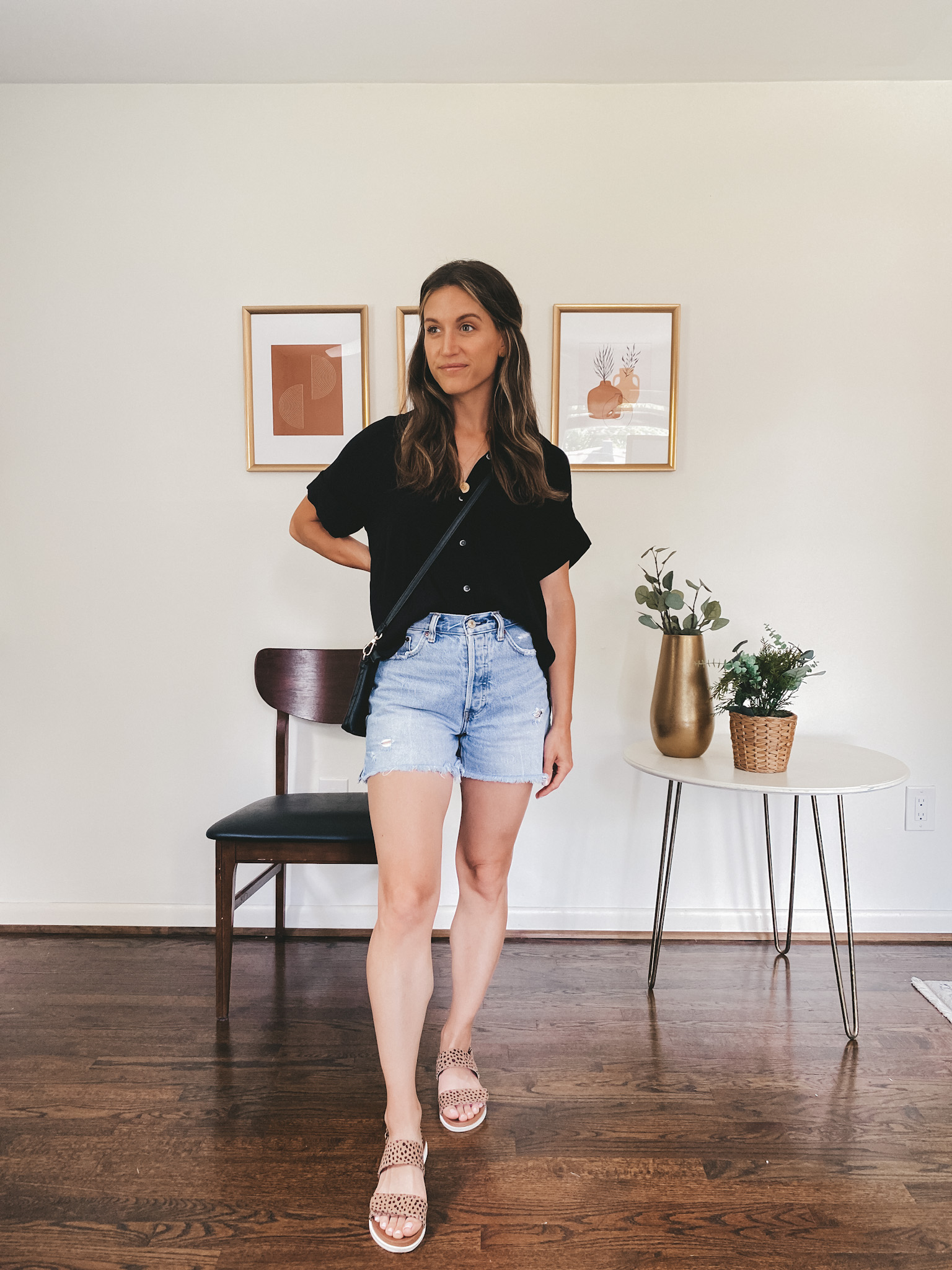 ashley wearing a drapey black button down, cut-off denim shorts and leopard print sandals