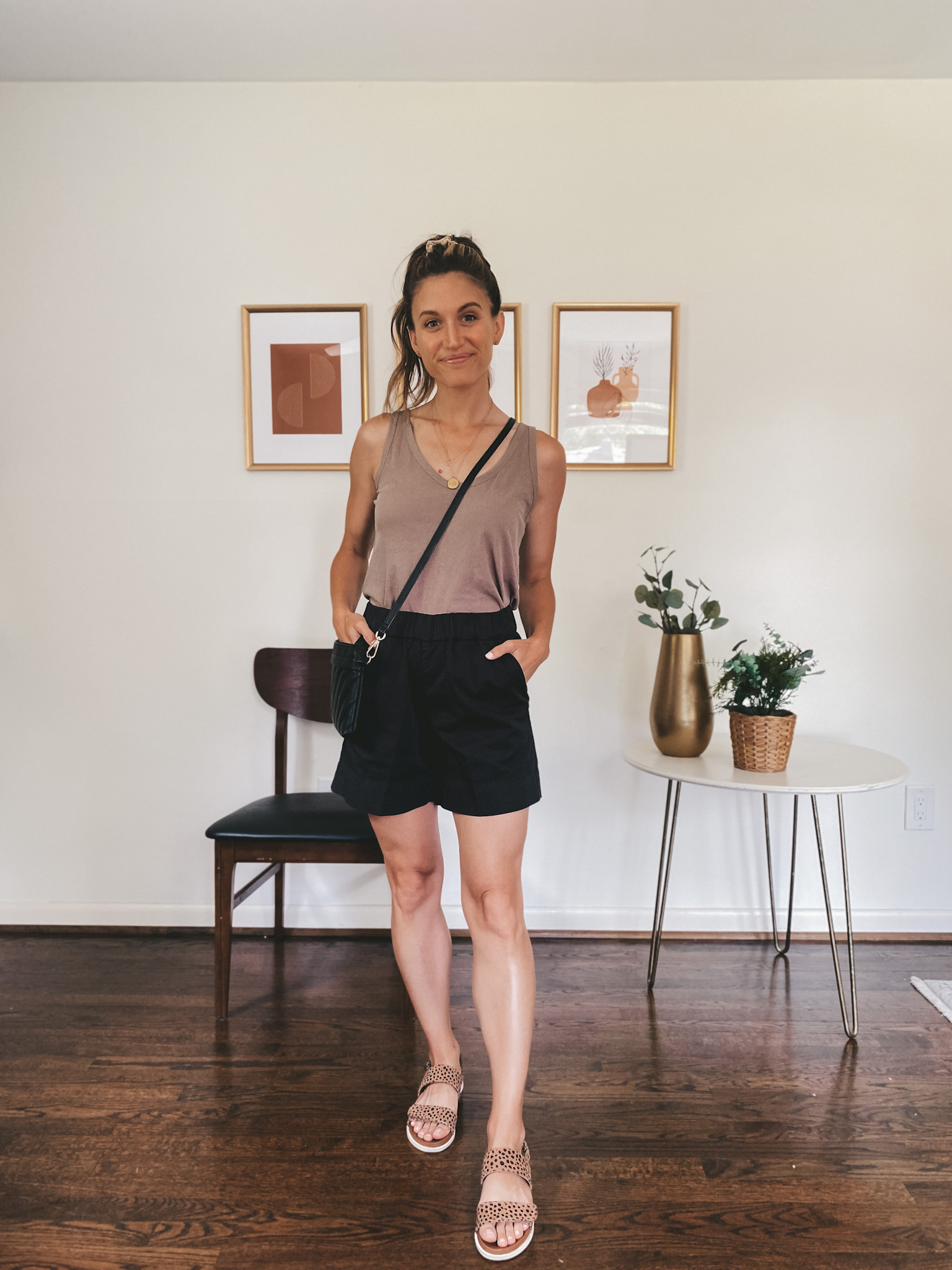 ashley wearing a taupe tank, black chino shorts, and leopard print sandals with a black crossbody bag