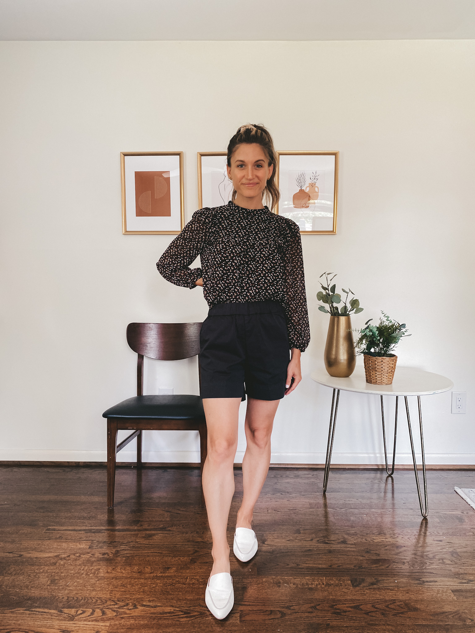 ashley wearing a black puff sleeve blouse, black chino shorts, and white mules