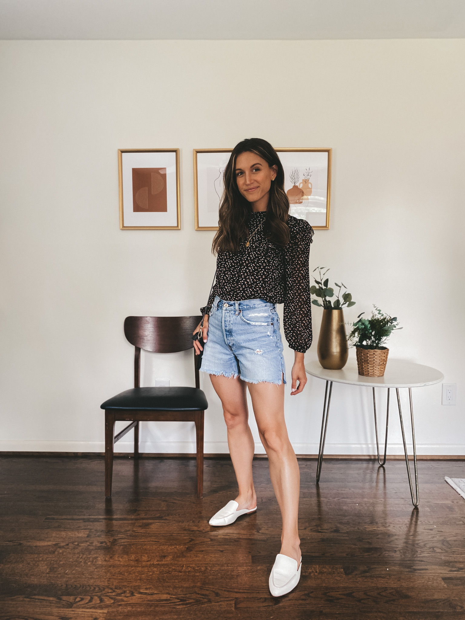 ashley wearing a black puff sleeve blouse, cut-off denim shorts, and white mules