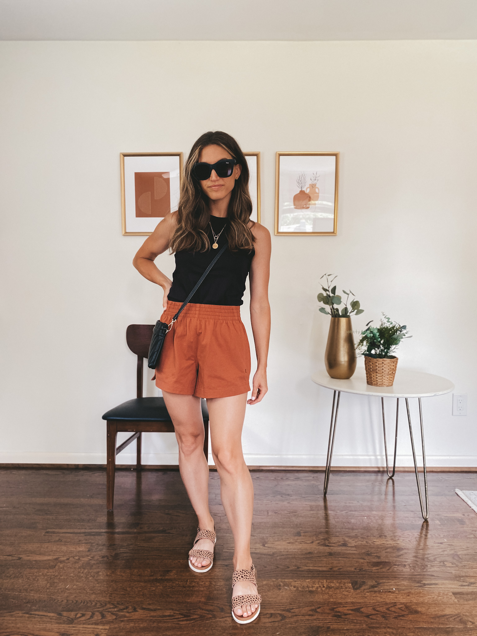 ashley wearing a black tank, rust colored jersey shorts and leopard print sandals with black square frame sunglasses