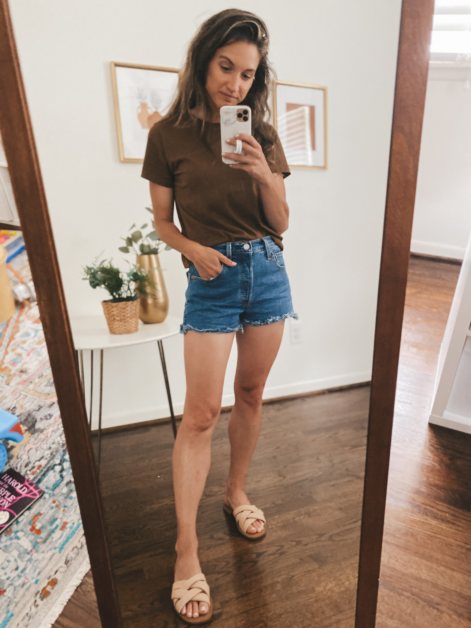 ashley wearing cut-off denim shorts, a walnut colored tee, and nude padded slides