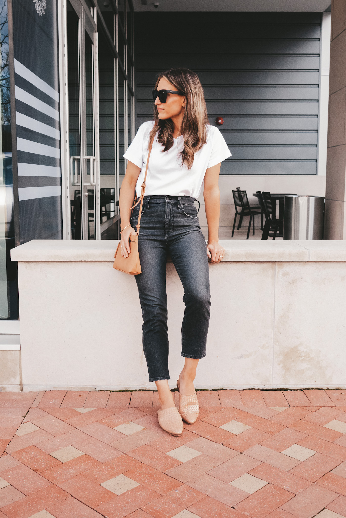 ashley leaning against a concrete wall next to a coffee shop