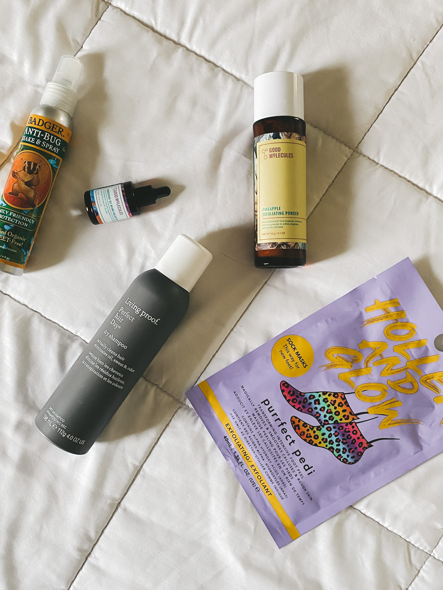 5 beauty and skincare products on a white blanket