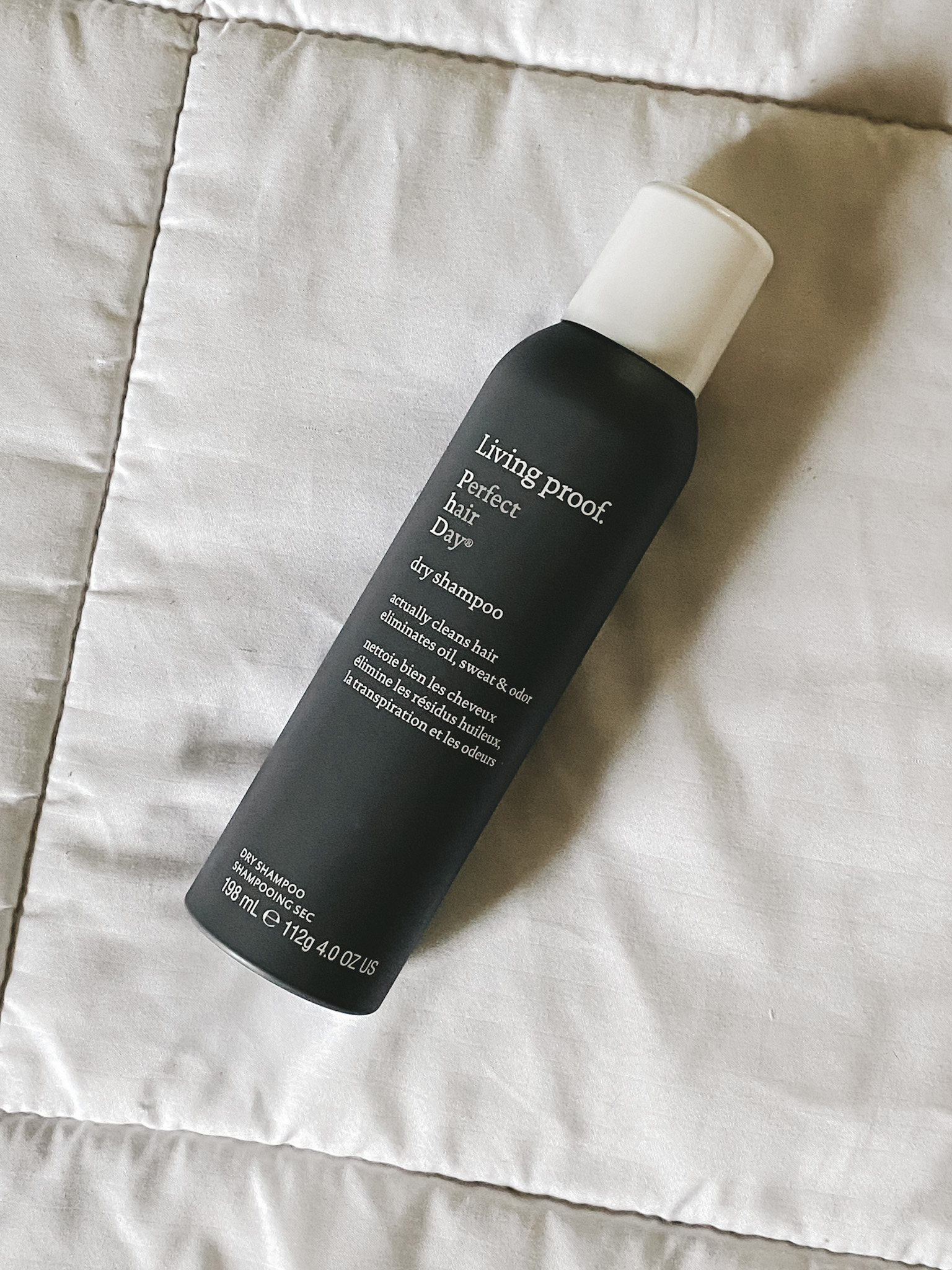 a white blanket with Living Proof Perfect Hair Day Dry Shampoo