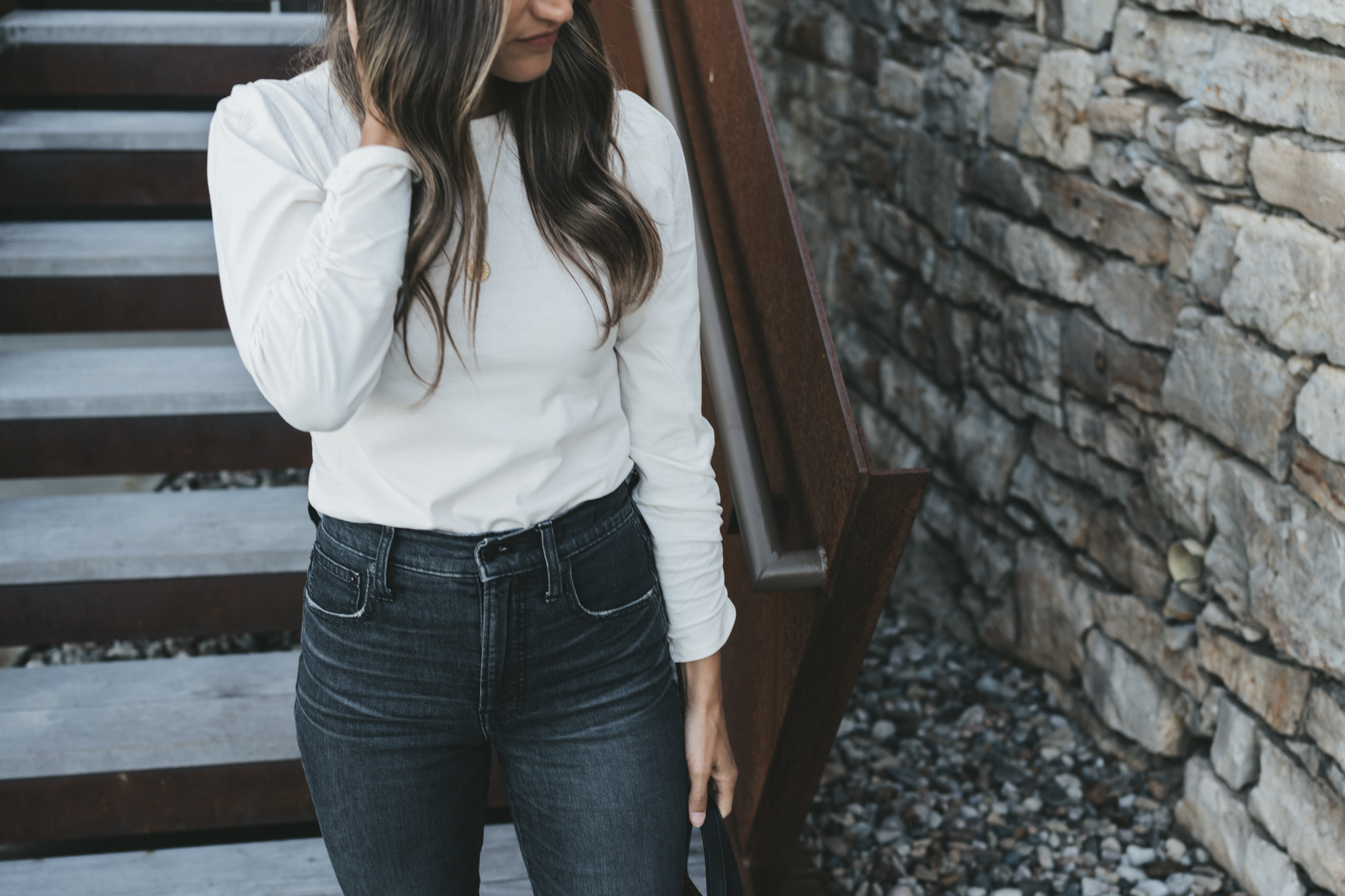 ashley wearing a white puff sleeve top with a ruched sleeve and washed black denim