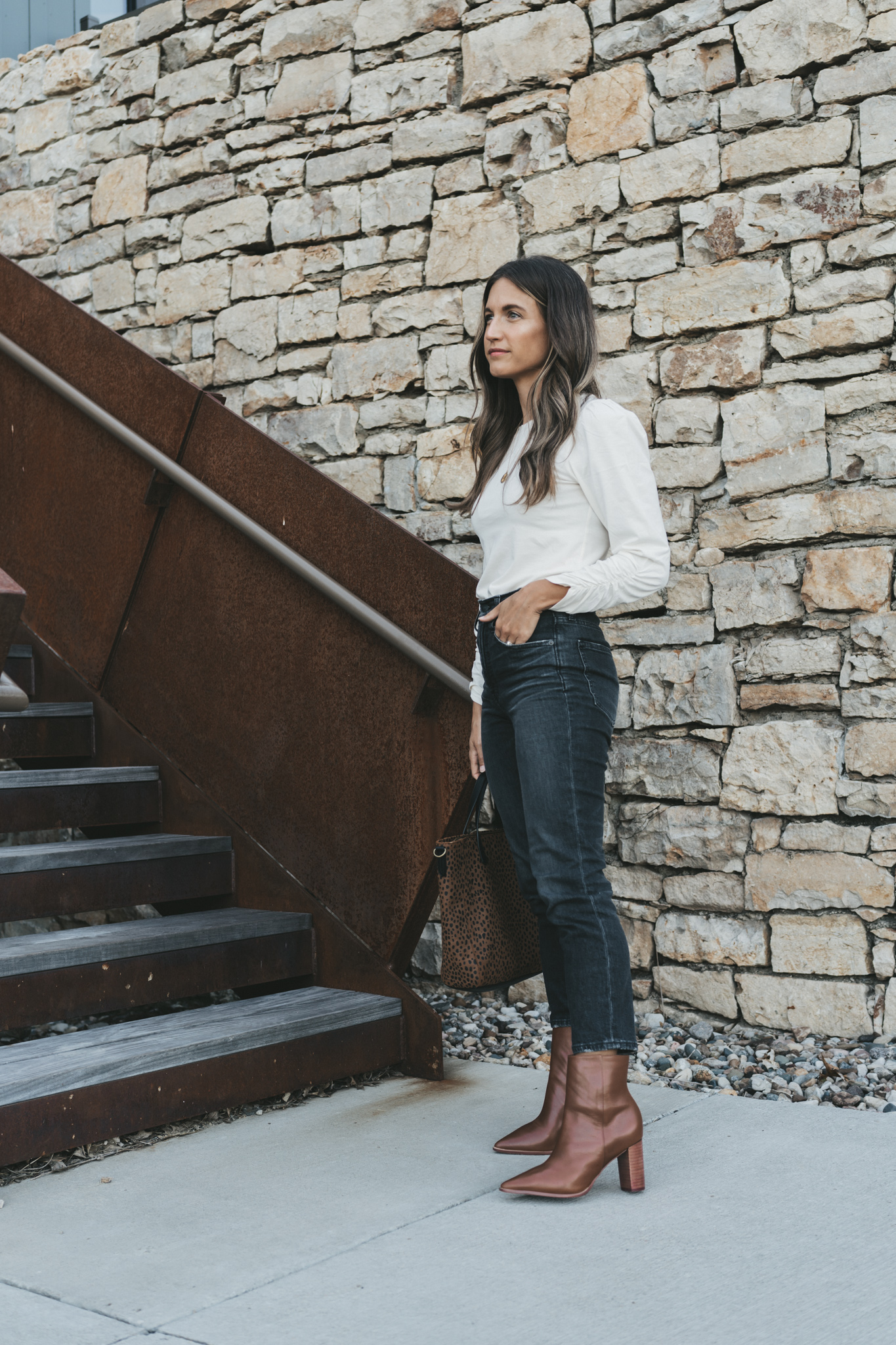 ashley wearing a white puff sleeve top with a ruched sleeve from ABLE, washed black denim and brown ankle boots