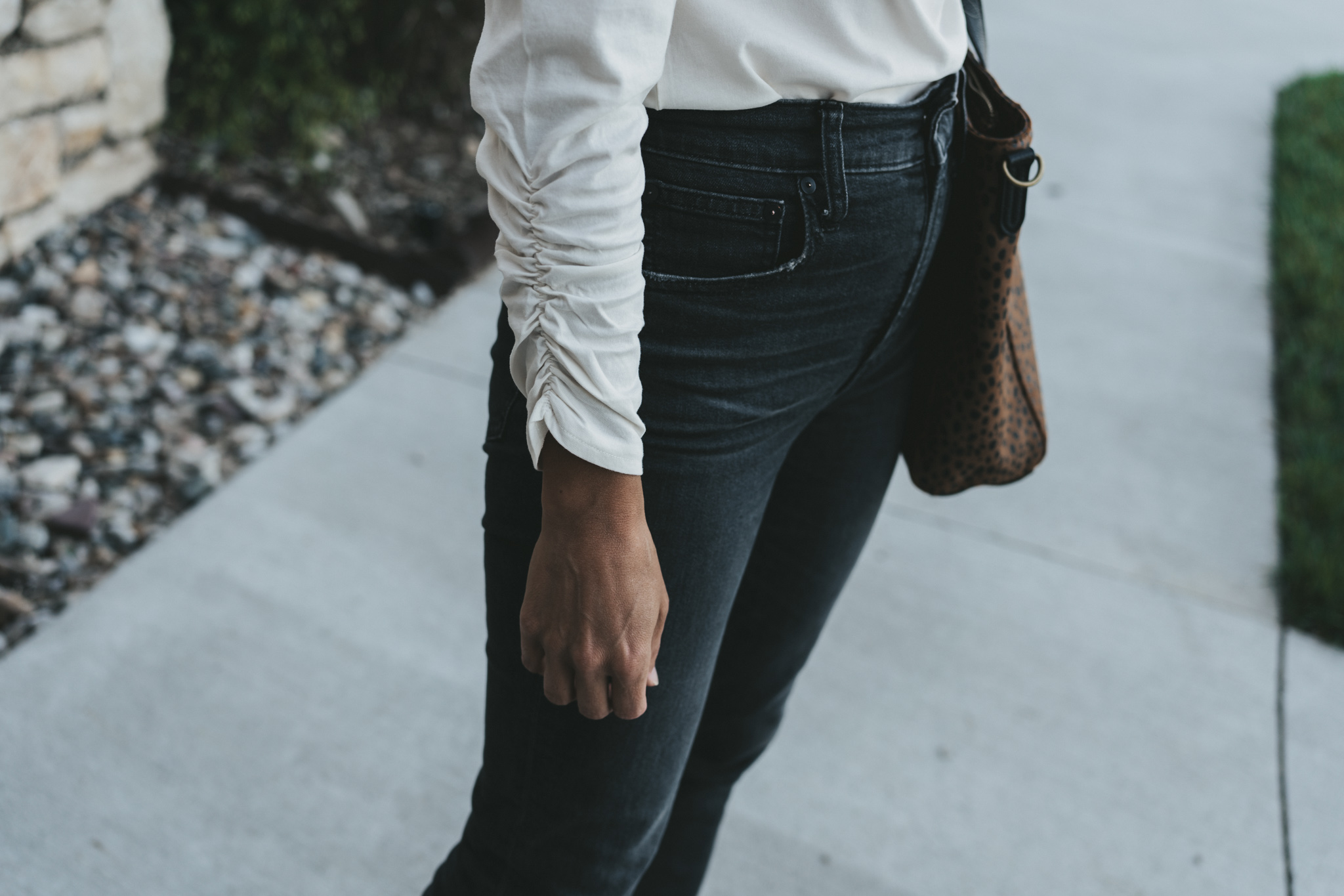 a close up picture of the ruched sleeve detail on a white top from ABLE