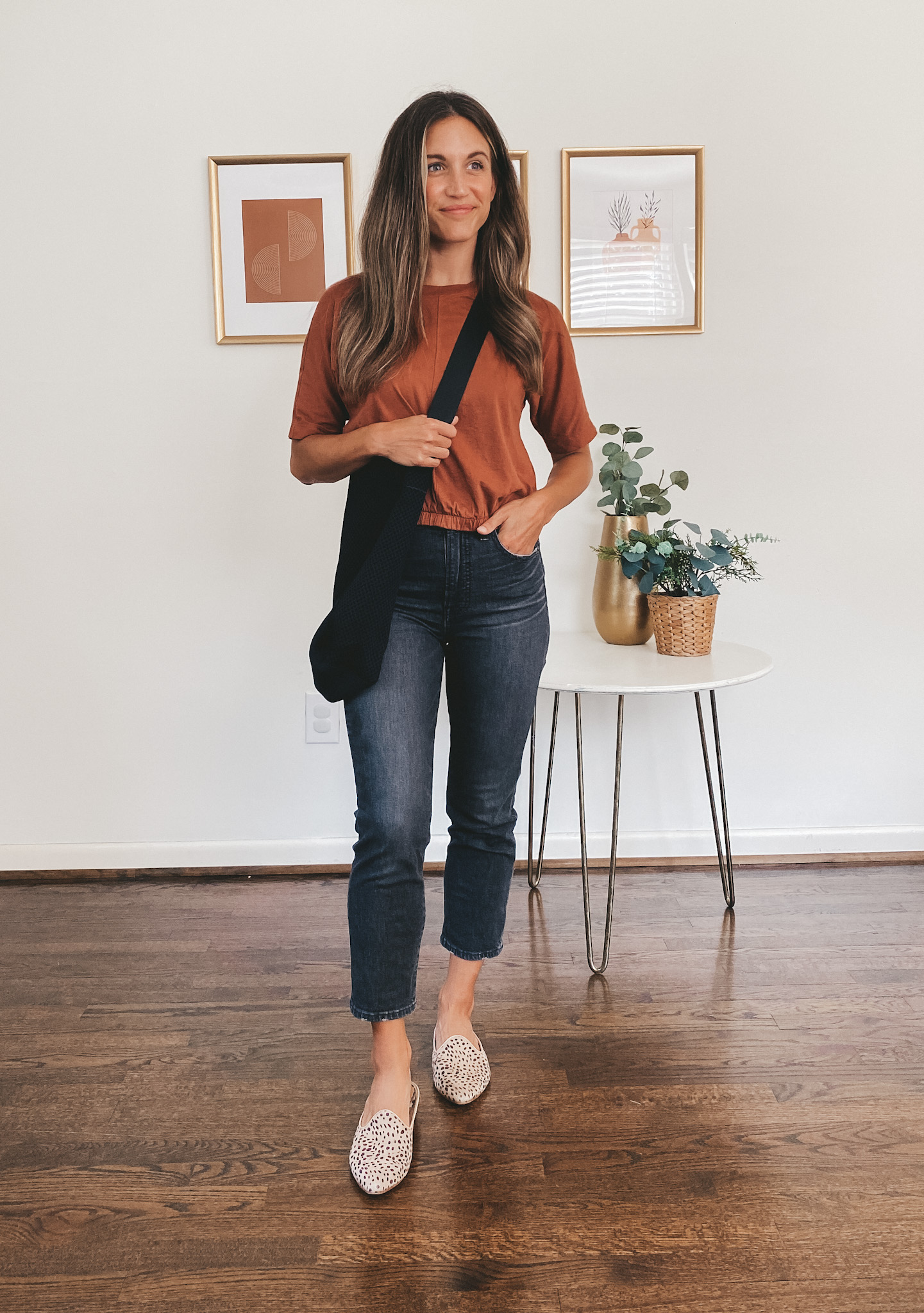 ashley wearing a rust colored tee, washed black denim, leopard print mules and a black tote bag