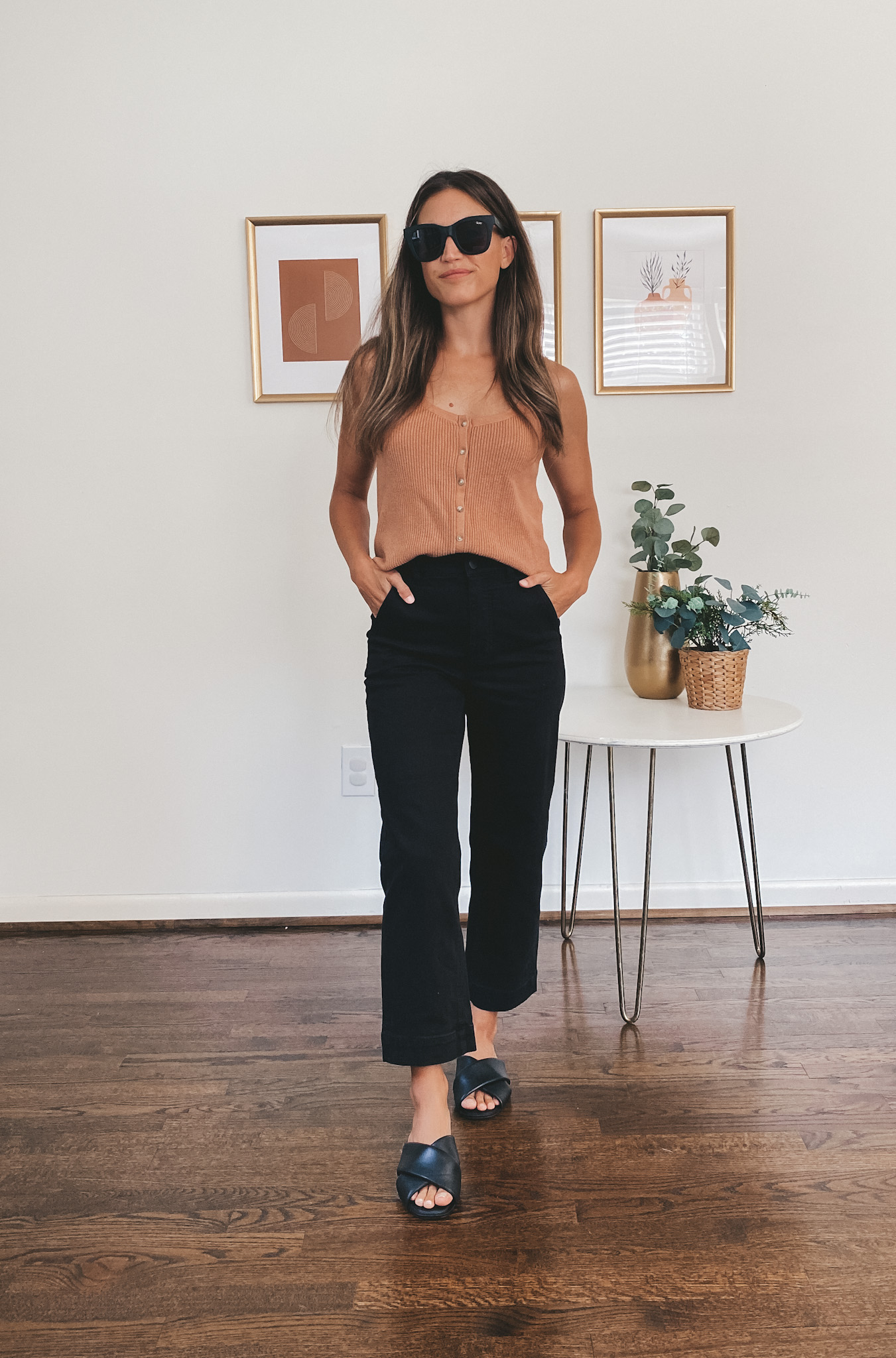 ashley wearing a light brown sweater tank with buttons down the front, black cropped pants and black crossover sandals