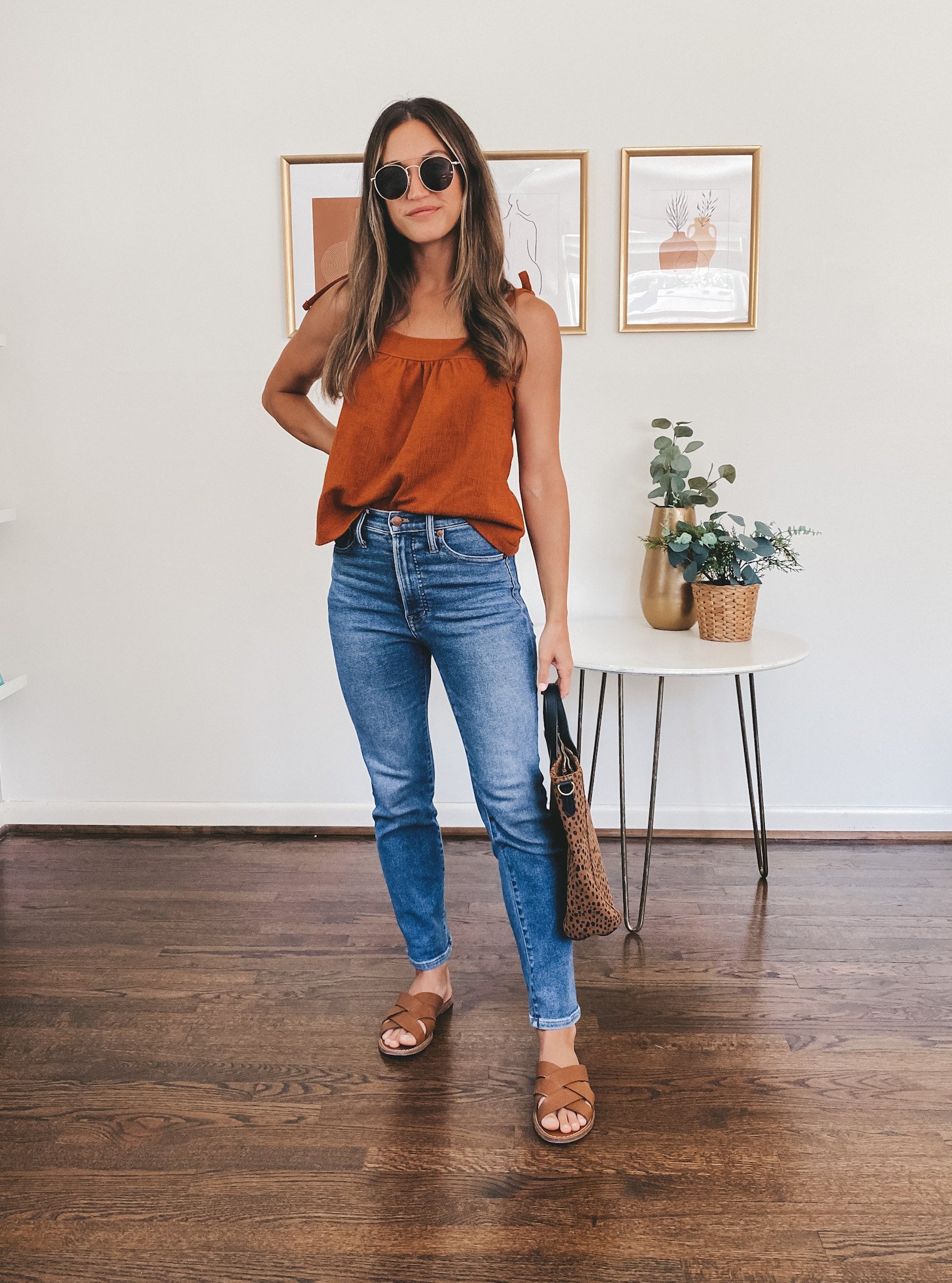 ashley wearing an dark orange tie strap tank, medium wash jeans, and braided slide sandals with a leopard print tote bag; early fall outfit