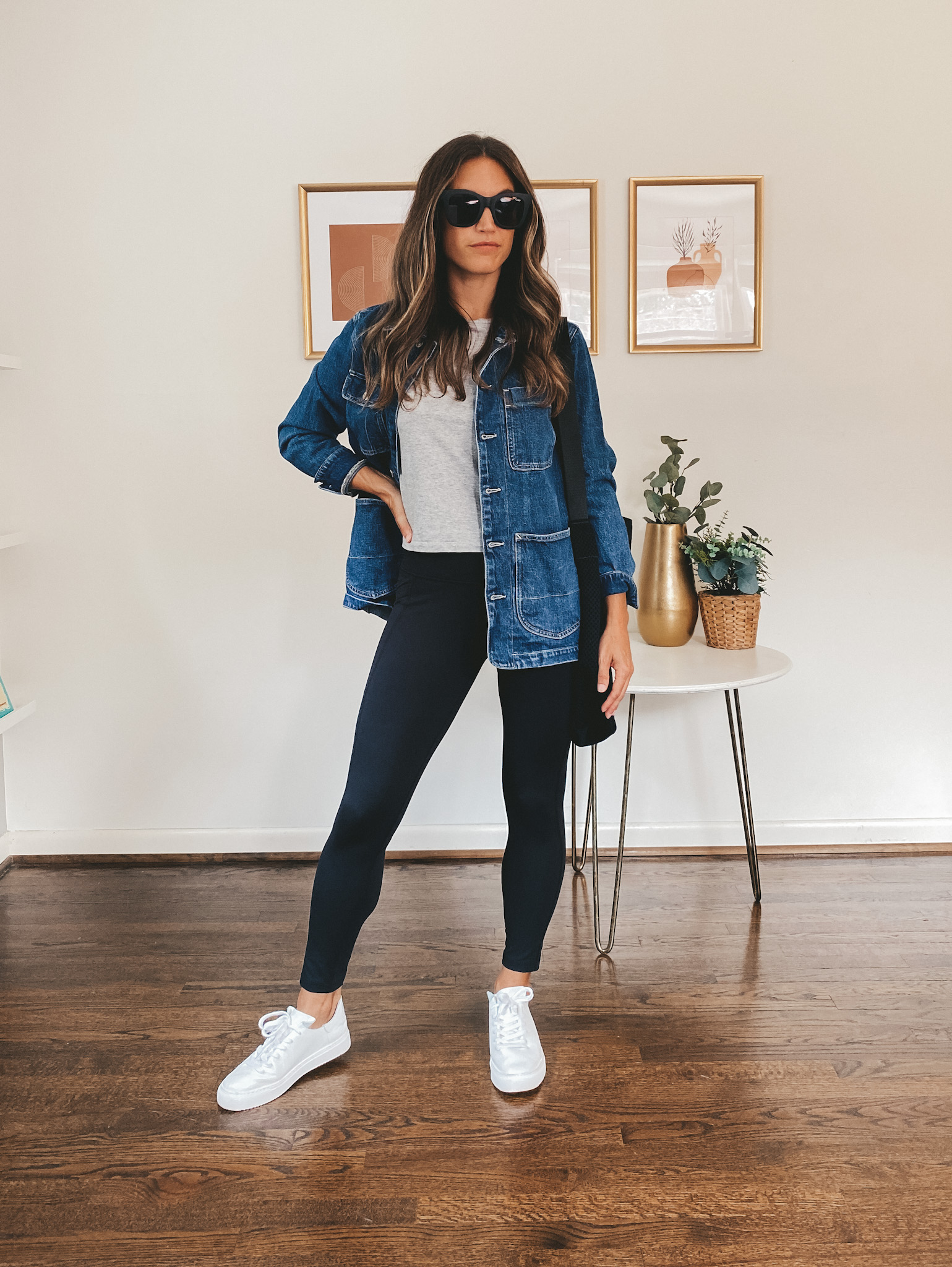 ashley wearing a gray tee, denim chore jacket, black leggings and white sneakers