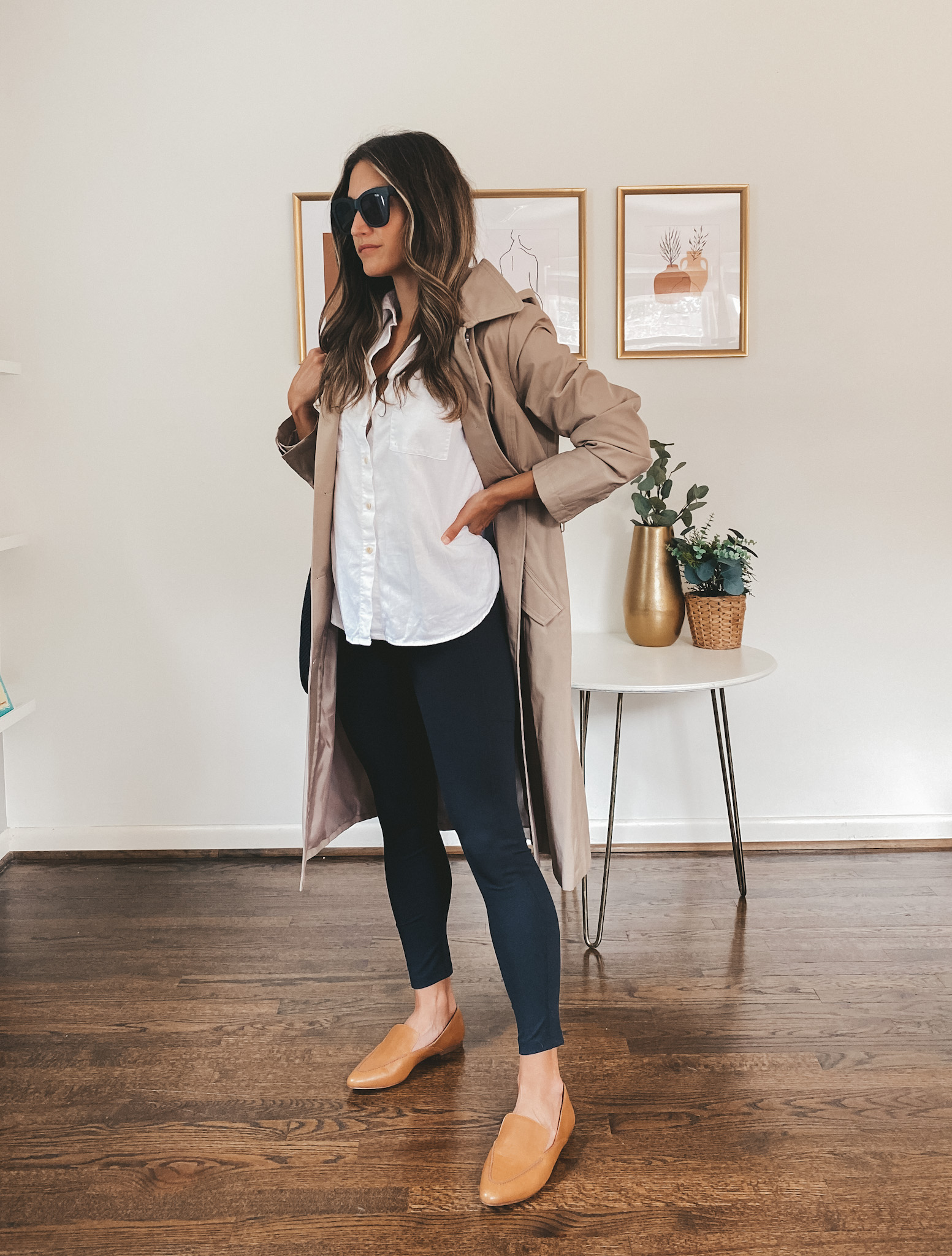 ashley wearing a white button down, trench coat, black leggings, and brown loafers