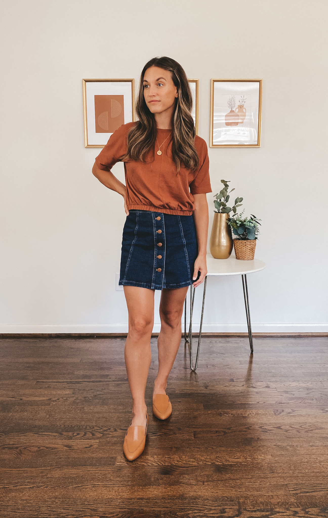 ashley wearing a dark orange tee, button front dark wash denim skirt, and cognac loafers