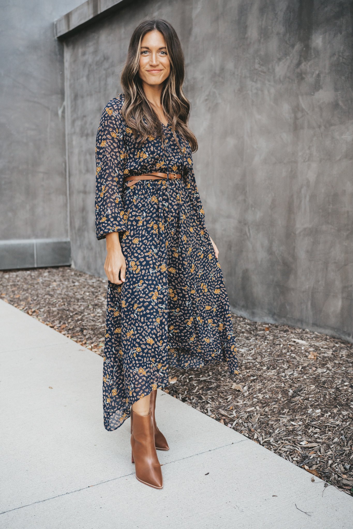 ashley wearing a navy floral midi dress belted at the waist with brown ankle boots