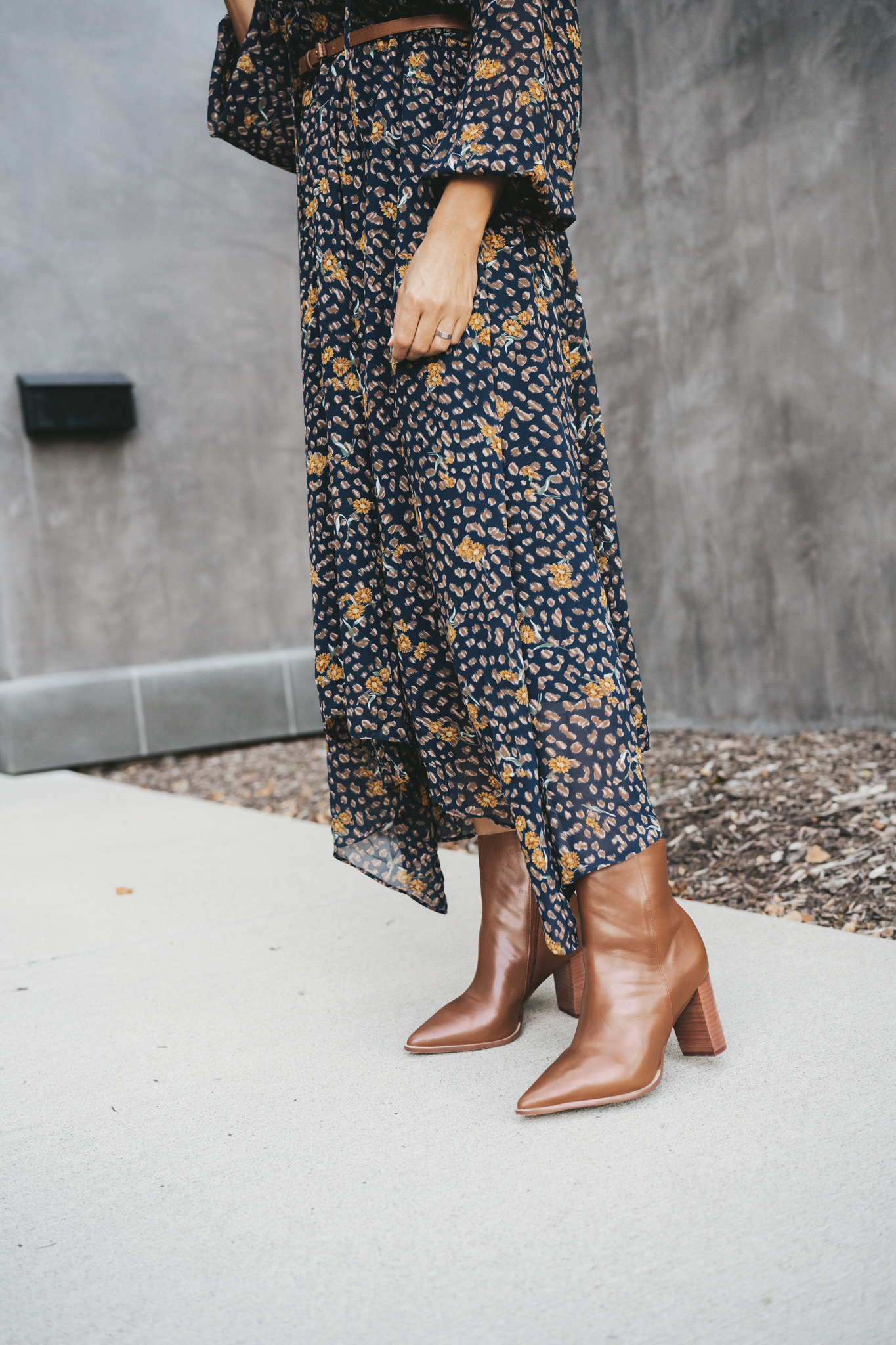 a waist down picture of Ashley wearing a navy floral midi dress and brown ankle boots